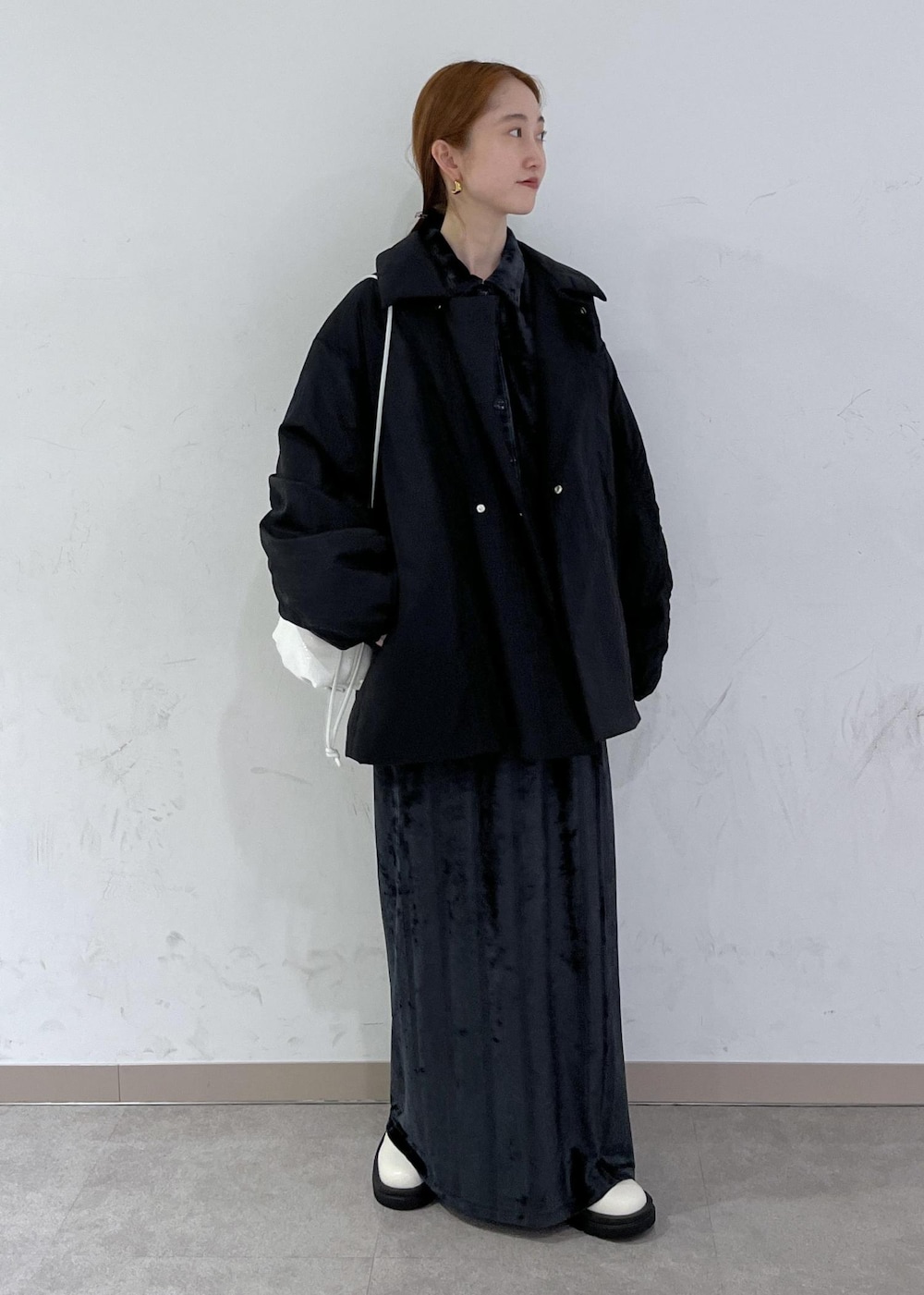 ホワイト系のブーツ、ブラック系のブルゾン、ホワイト系のハンドバッグを着用したレディースの秋コーディネートの3枚目の写真