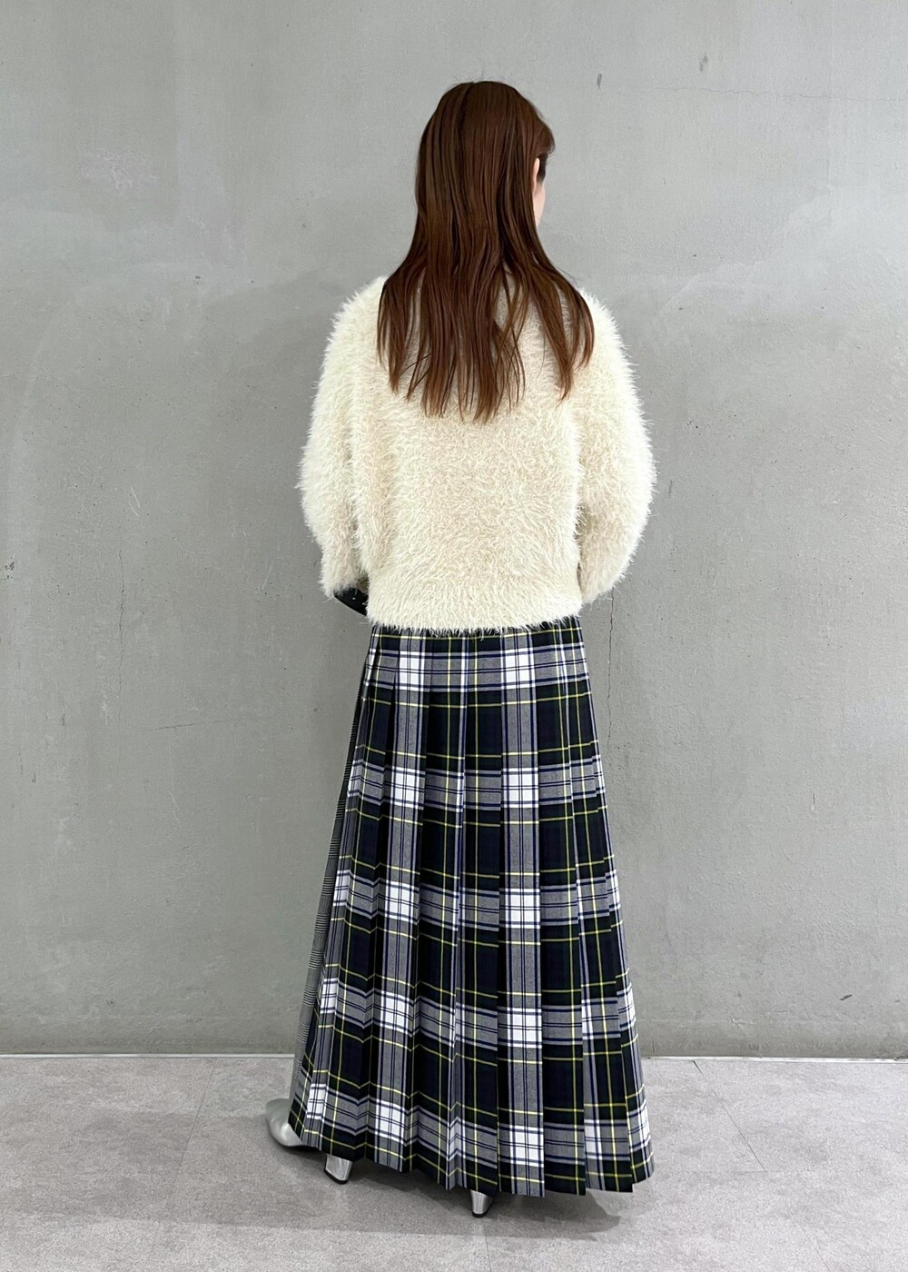 シルバー系のブーツ、ホワイト系のニット/セーター、グリーン系のスカートを着用したレディースの秋コーディネートの2枚目の写真