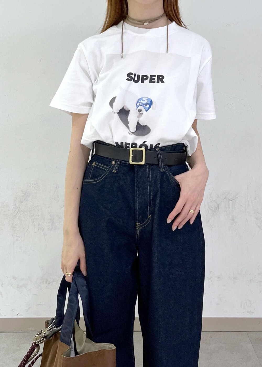 ブラウン系のトートバッグ、ブルー系のデニムパンツ、シルバー系のネックレスを着用したレディースの夏コーディネートの6枚目の写真