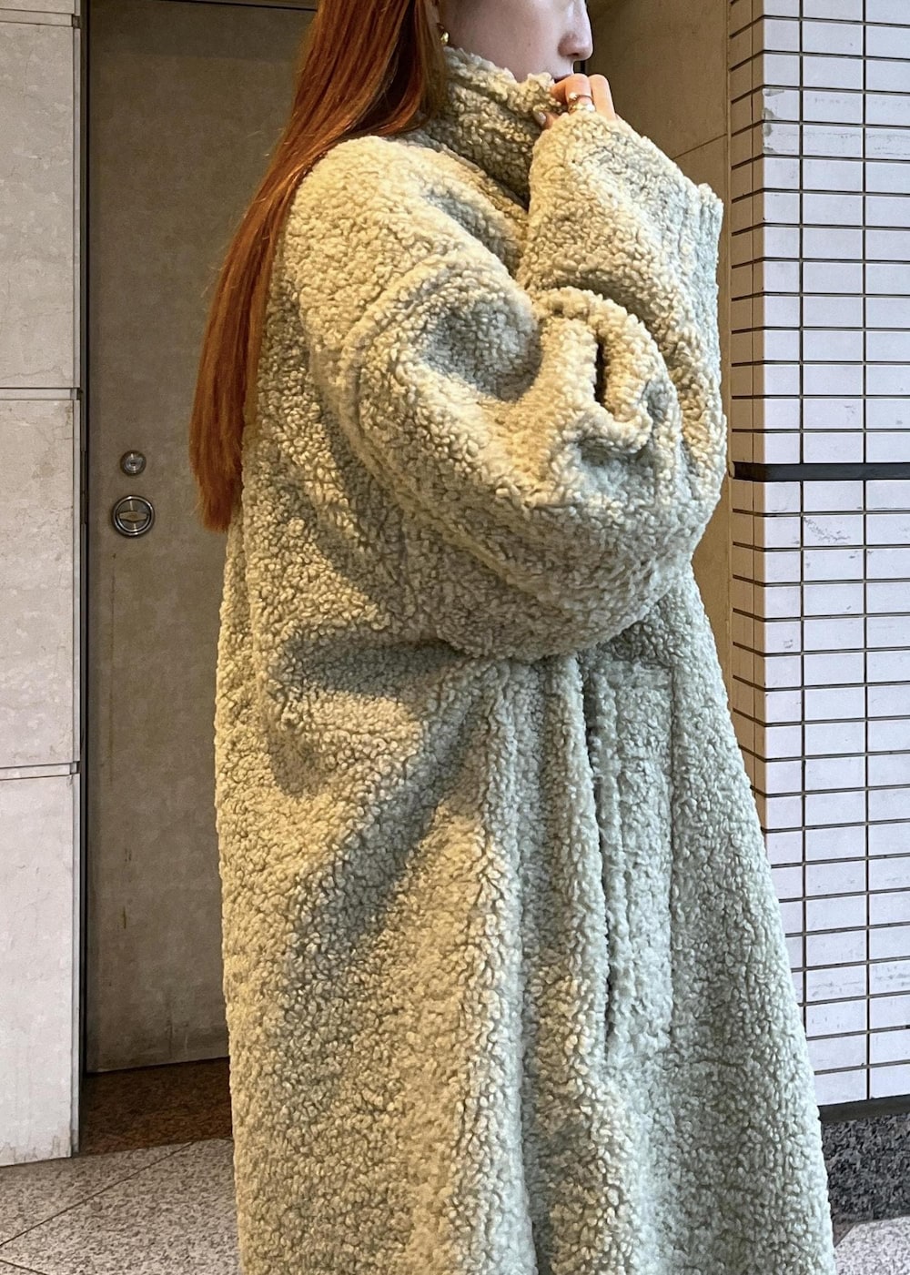 ブラック系のブーツ、ホワイト系のカーディガン/ボレロ、グリーン系のその他アウターを着用したレディースの冬コーディネートの10枚目の写真