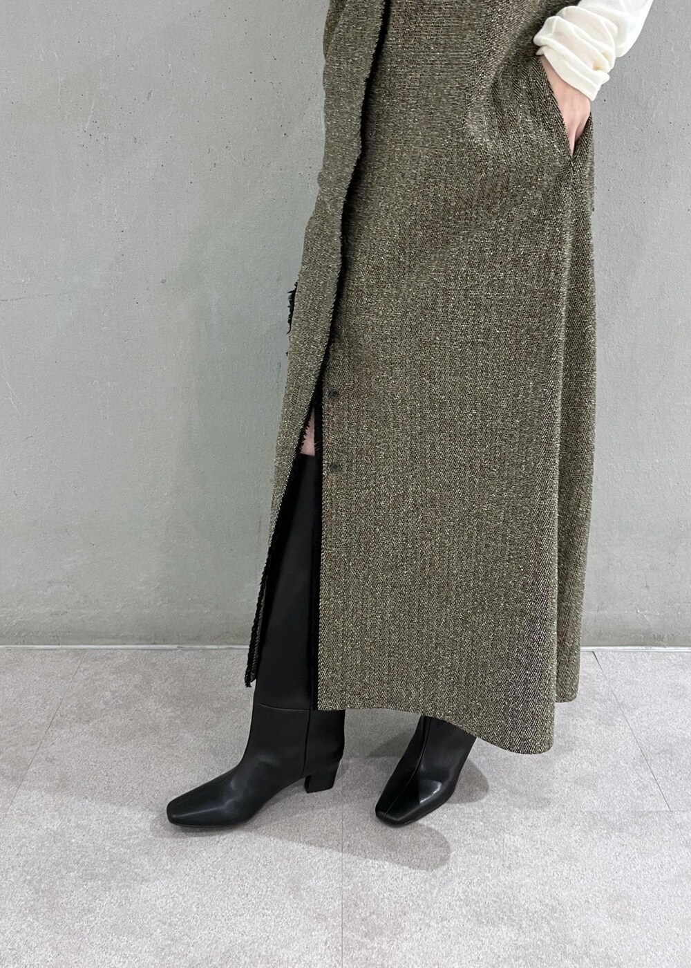 ブラック系のブーツ、ベージュ系のワンピース、ホワイト系のTシャツ/カットソーを着用したレディースの秋コーディネートの6枚目の写真