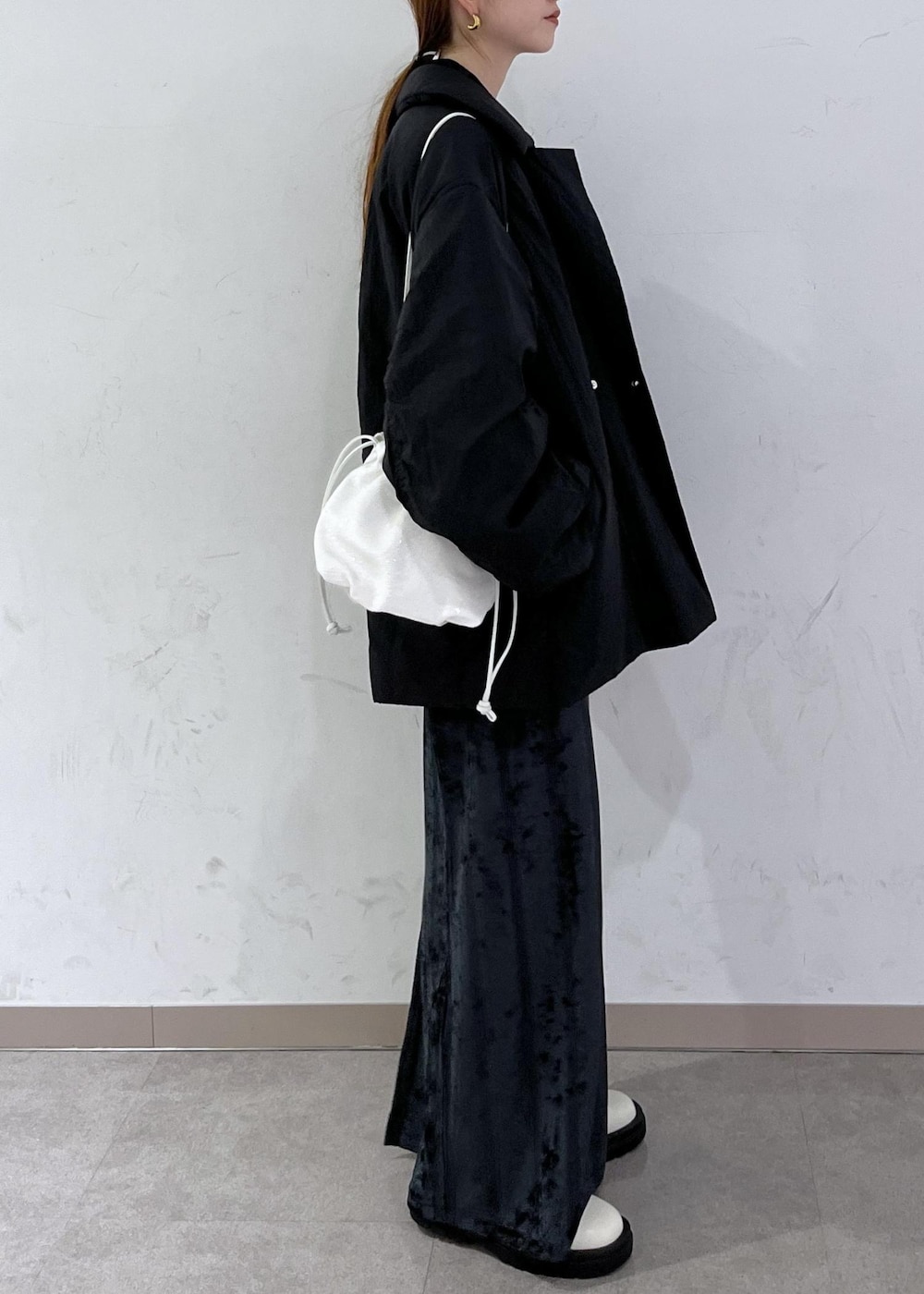 ホワイト系のブーツ、ブラック系のブルゾン、ホワイト系のハンドバッグを着用したレディースの秋コーディネートの4枚目の写真