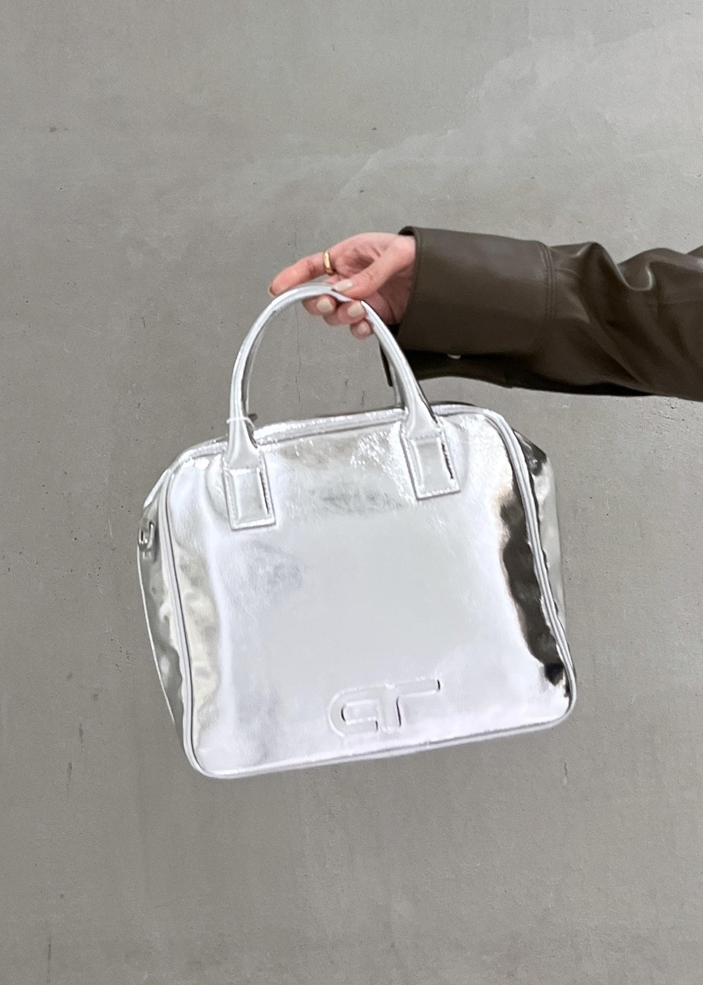 ブラウン系のブルゾン、シルバー系のボストンバッグ、ブラック系のスカートを着用したレディースの夏コーディネートの5枚目の写真