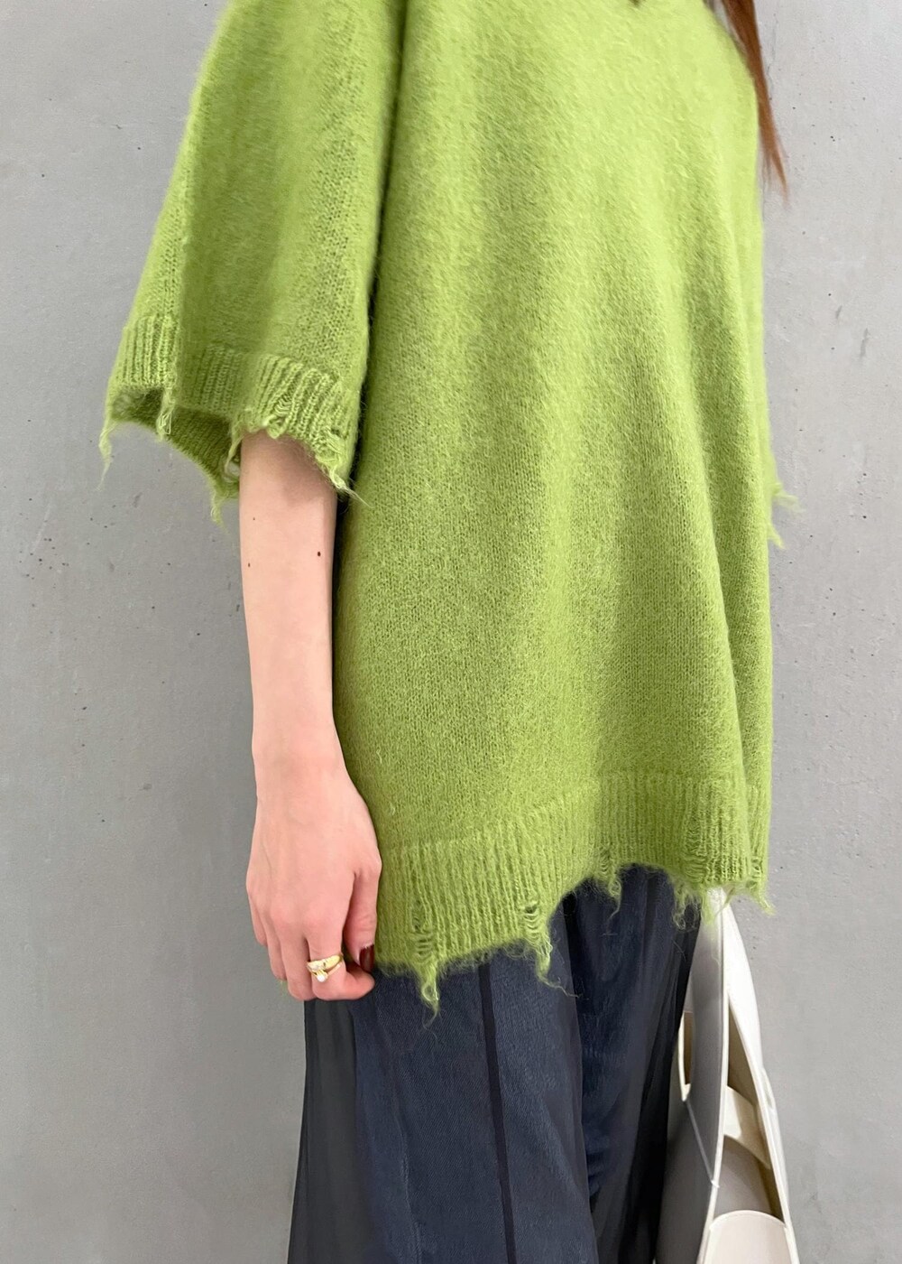 ブラック系のブーツ、ホワイト系のハンドバッグ、ブルー系のデニムパンツを着用したレディースの秋コーディネートの8枚目の写真