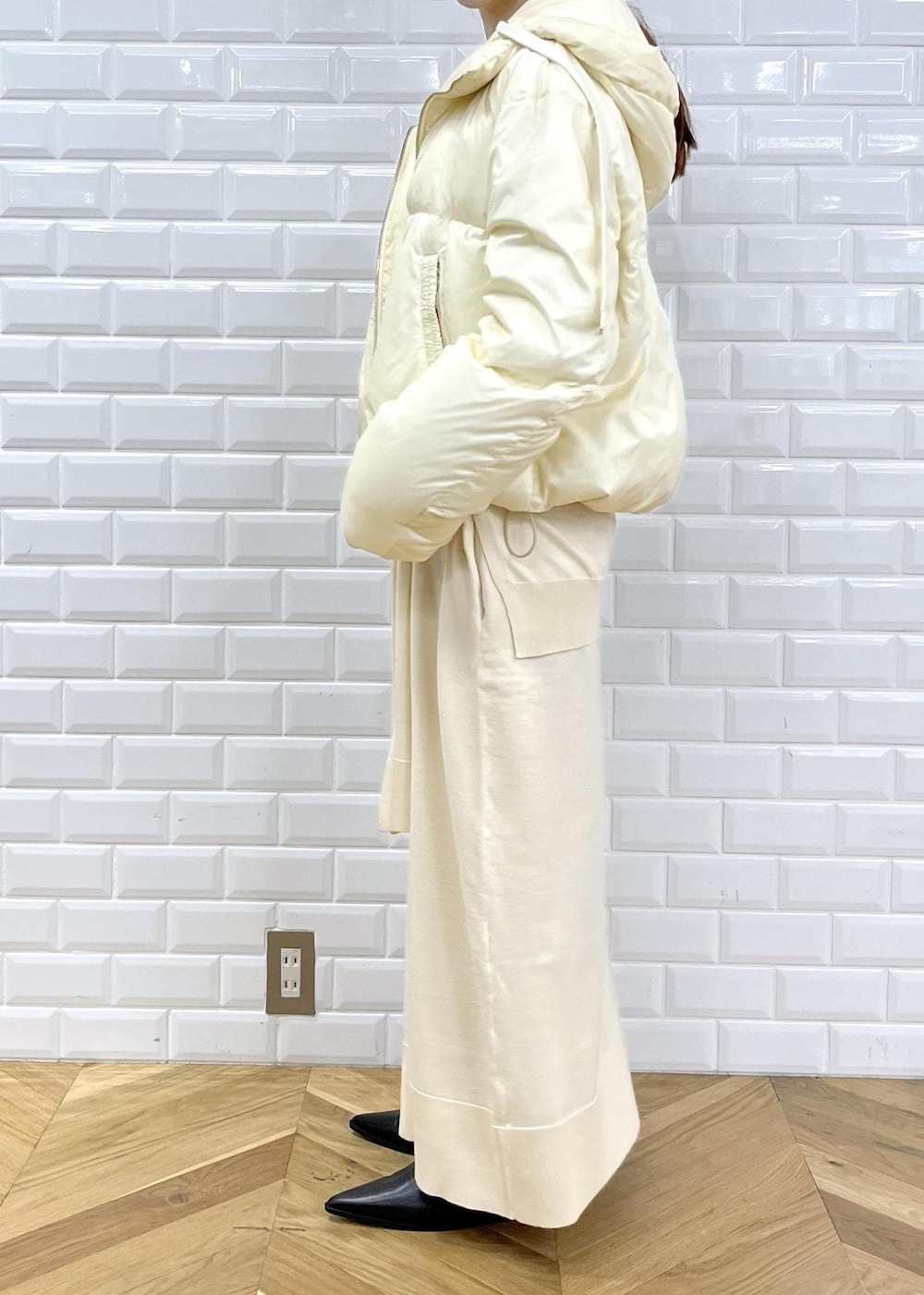 ブラック系のブーツ、ホワイト系のワンピース、ホワイト系のダウンジャケット/コートを着用したレディースの秋コーディネートの3枚目の写真