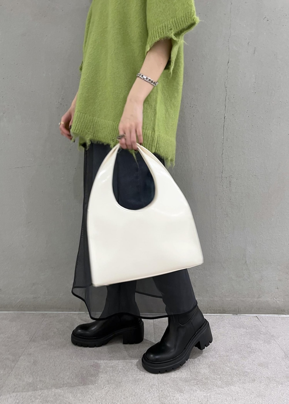 ブラック系のブーツ、ホワイト系のハンドバッグ、ブルー系のデニムパンツを着用したレディースの秋コーディネートの7枚目の写真