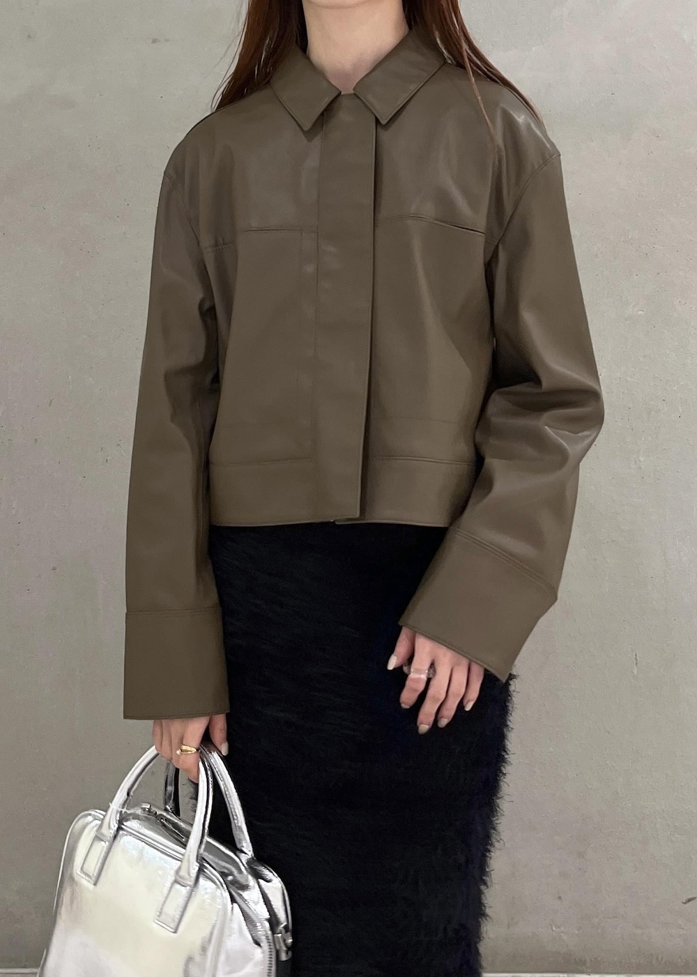 ブラウン系のブルゾン、シルバー系のボストンバッグ、ブラック系のスカートを着用したレディースの夏コーディネートの3枚目の写真