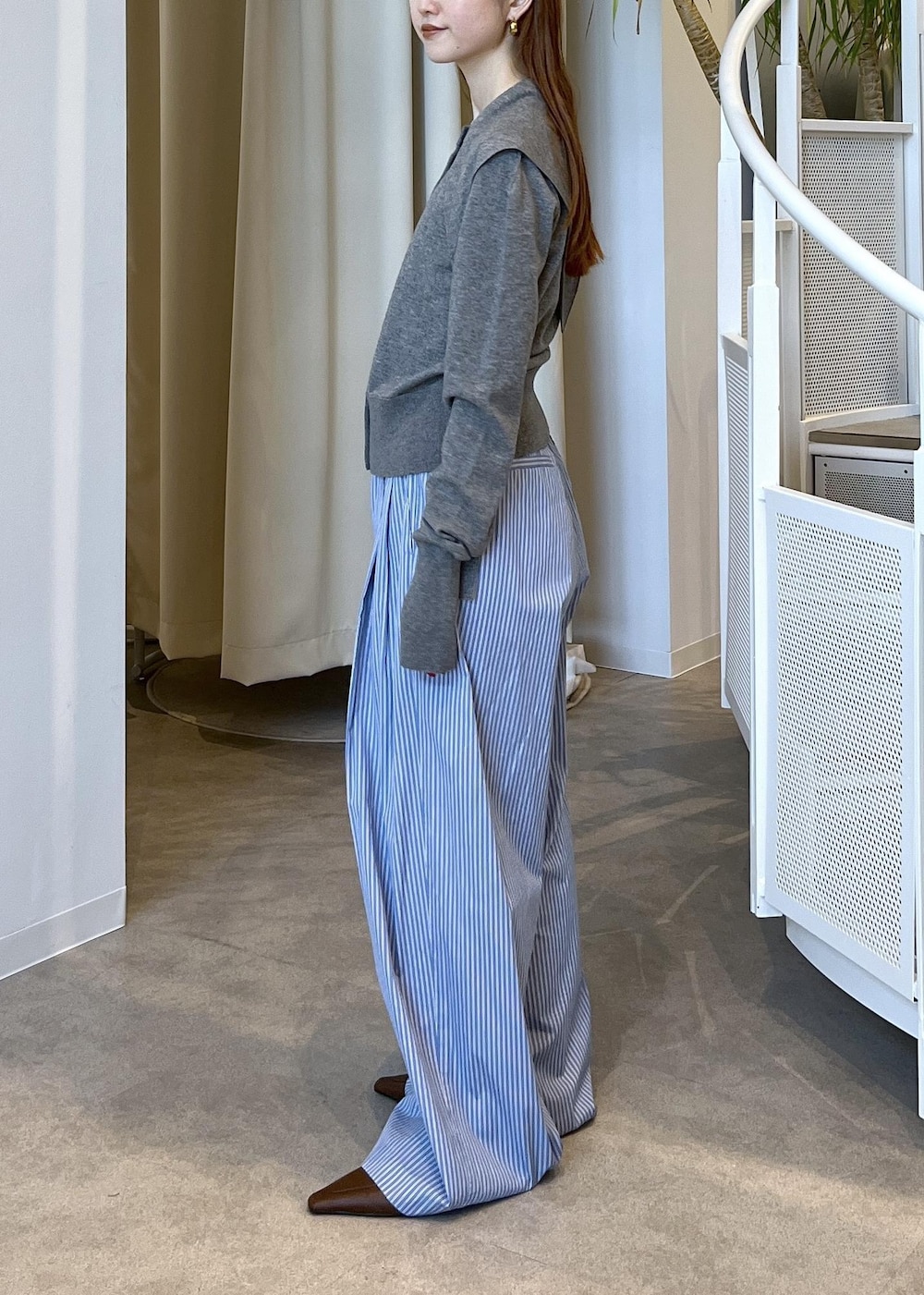 ブラウン系のサンダル、ブルー系のスラックス、グレー系のカーディガン/ボレロを着用したレディースの秋コーディネートの5枚目の写真