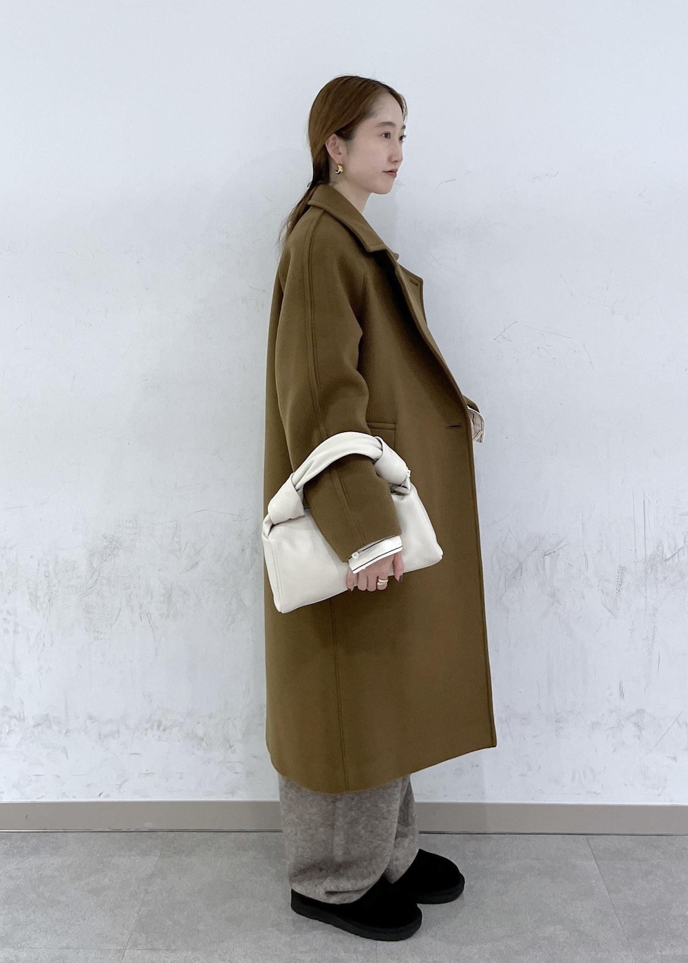 ホワイト系のハンドバッグ、イエロー系のステンカラーコート、ベージュ系のニット/セーターを着用したレディースの秋コーディネートの3枚目の写真