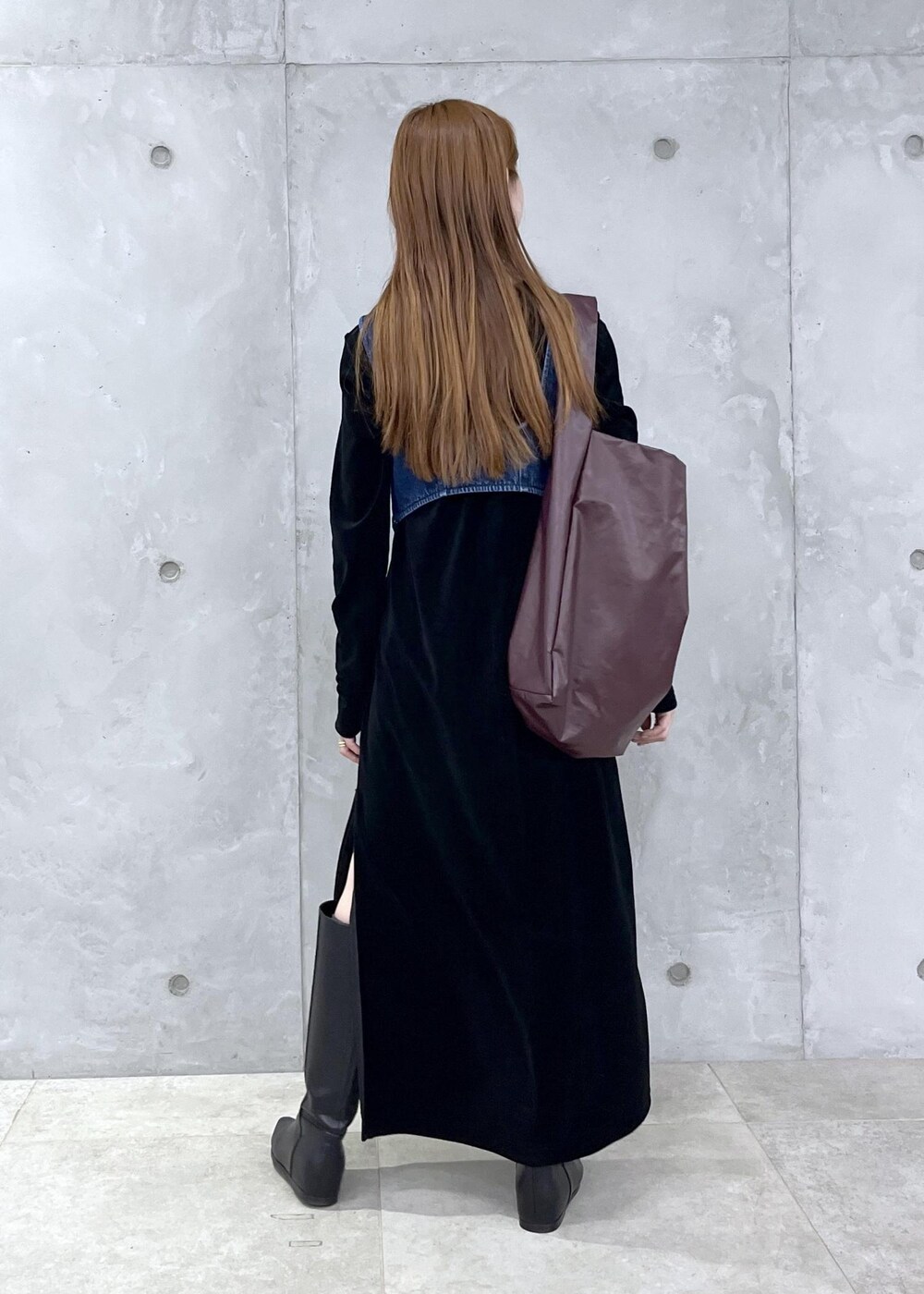 ブラック系のブーツ、ブラック系のワンピース、ブルー系のベストを着用したレディースの秋コーディネートの3枚目の写真