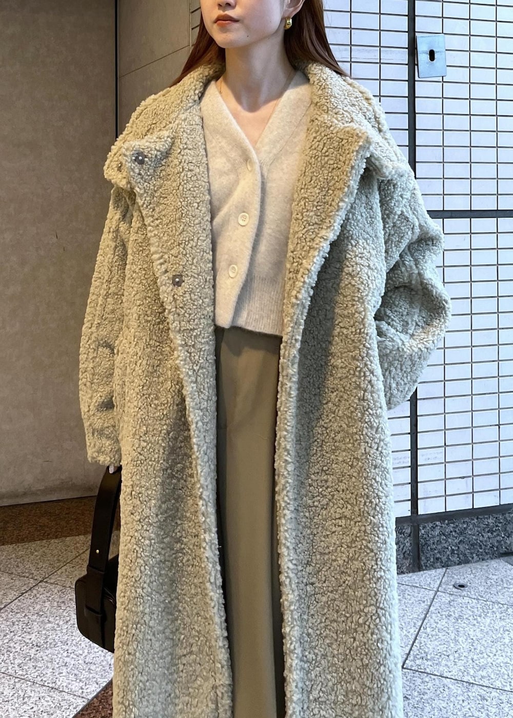 ブラック系のブーツ、ホワイト系のカーディガン/ボレロ、グリーン系のその他アウターを着用したレディースの冬コーディネートの6枚目の写真