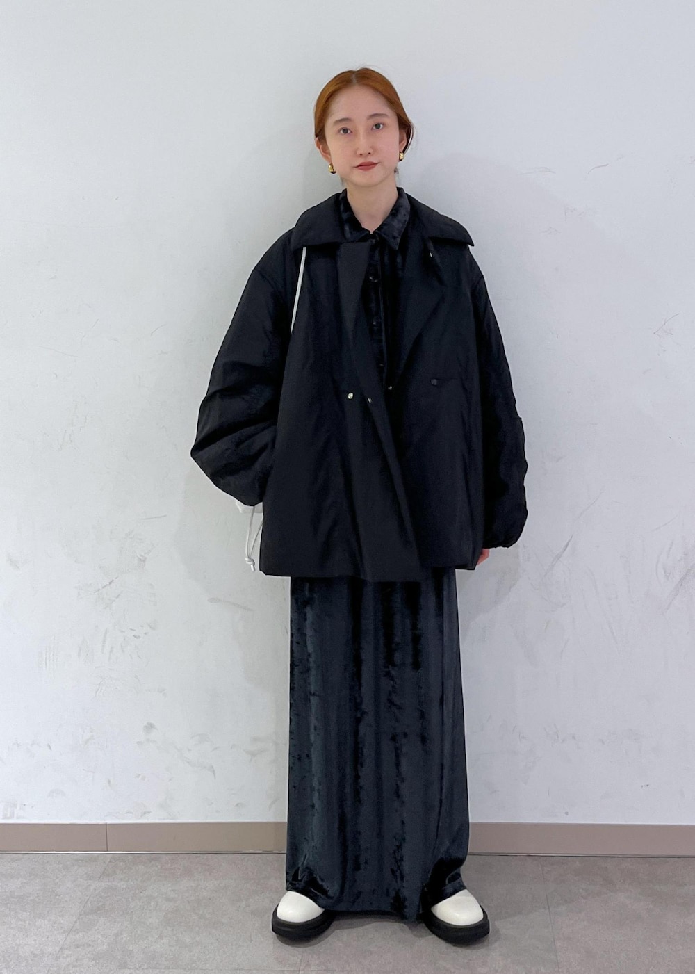 ホワイト系のブーツ、ブラック系のブルゾン、ホワイト系のハンドバッグを着用したレディースの秋コーディネートの2枚目の写真