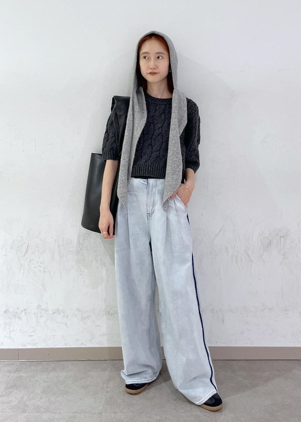 ブルー系のデニムパンツ、ブラック系のショルダーバッグ、グレー系のニット/セーターを着用したレディースの秋コーディネートの2枚目の写真