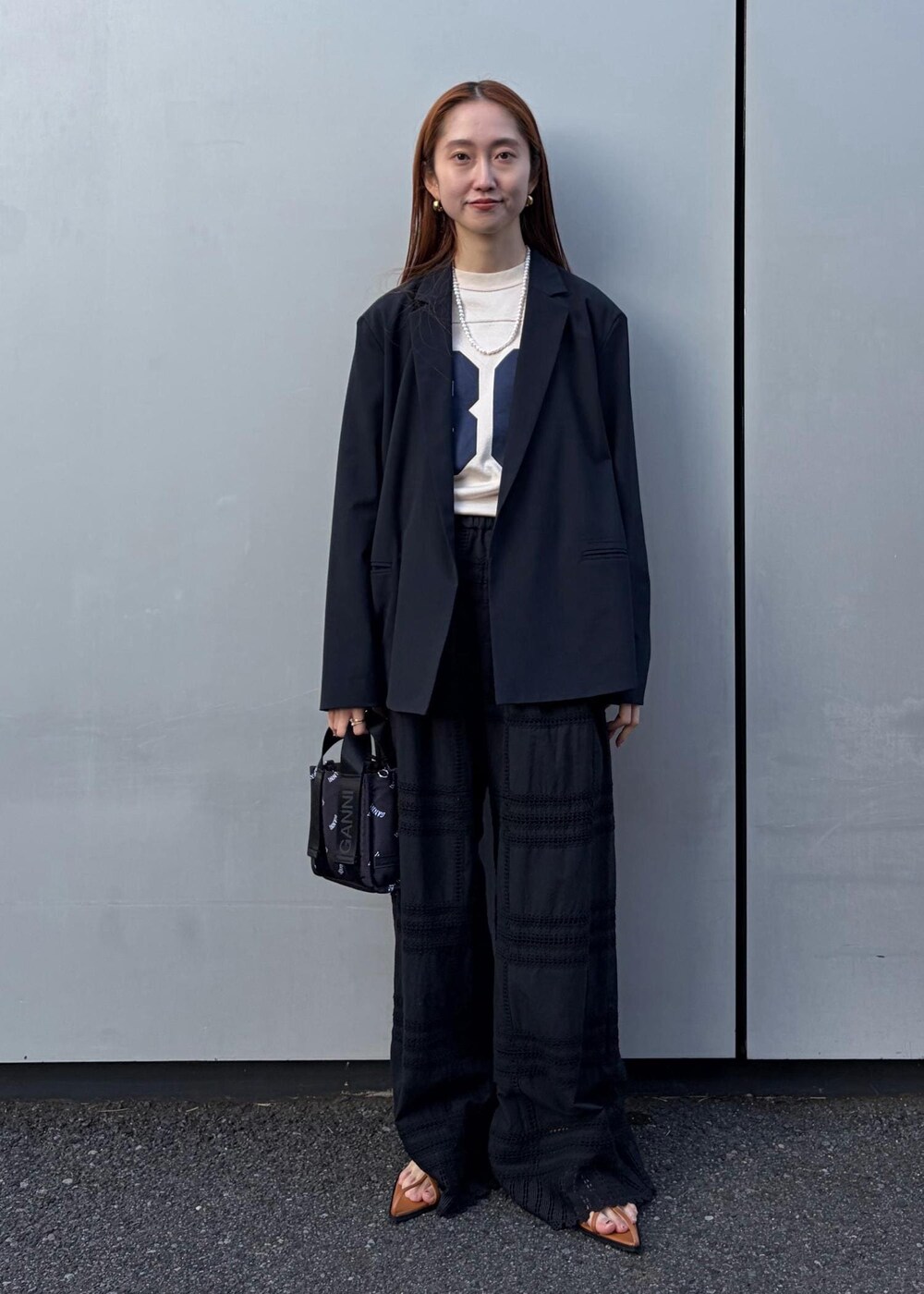 イエロー系のサンダル、ブラック系のトートバッグ、ホワイト系のネックレスを着用したレディースの冬コーディネートの2枚目の写真