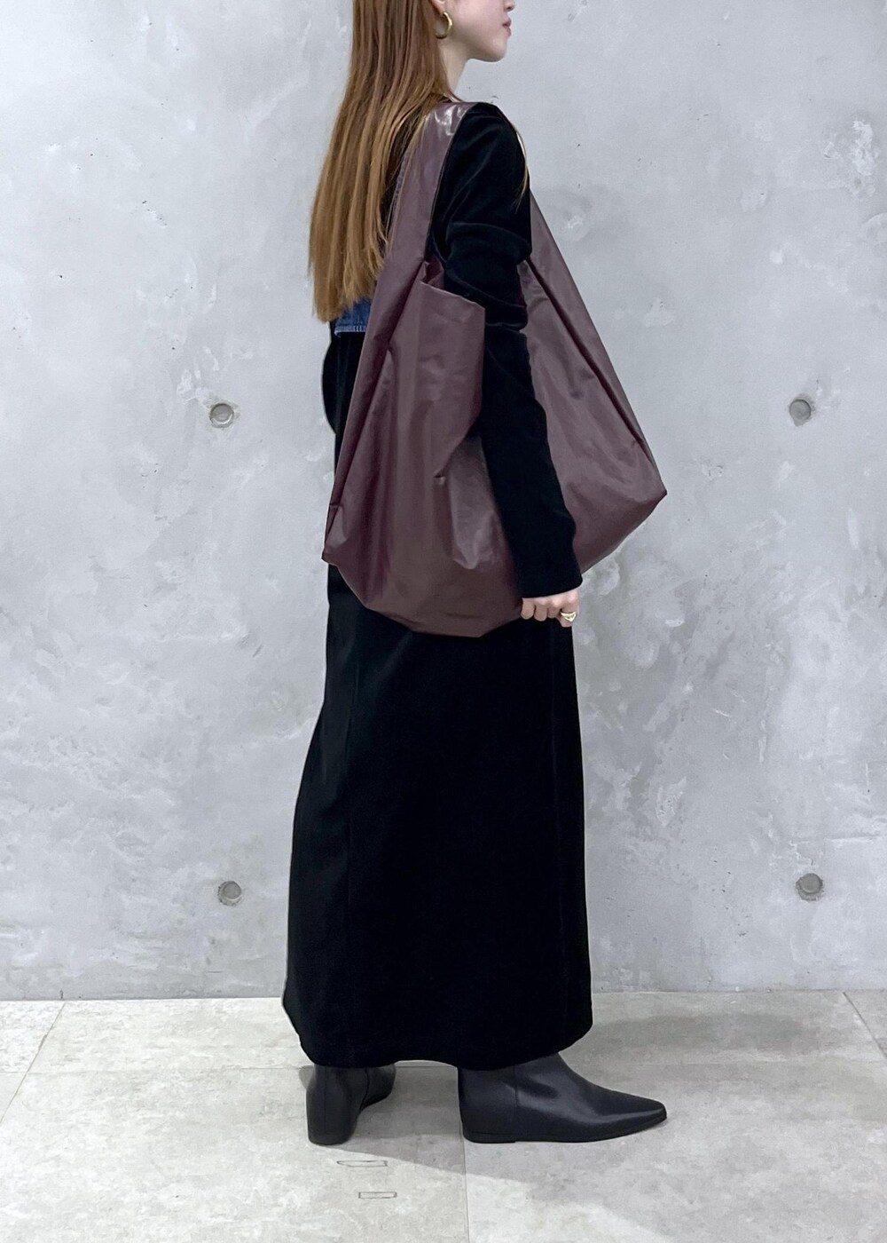 ブラック系のブーツ、ブラック系のワンピース、ブルー系のベストを着用したレディースの秋コーディネートの4枚目の写真