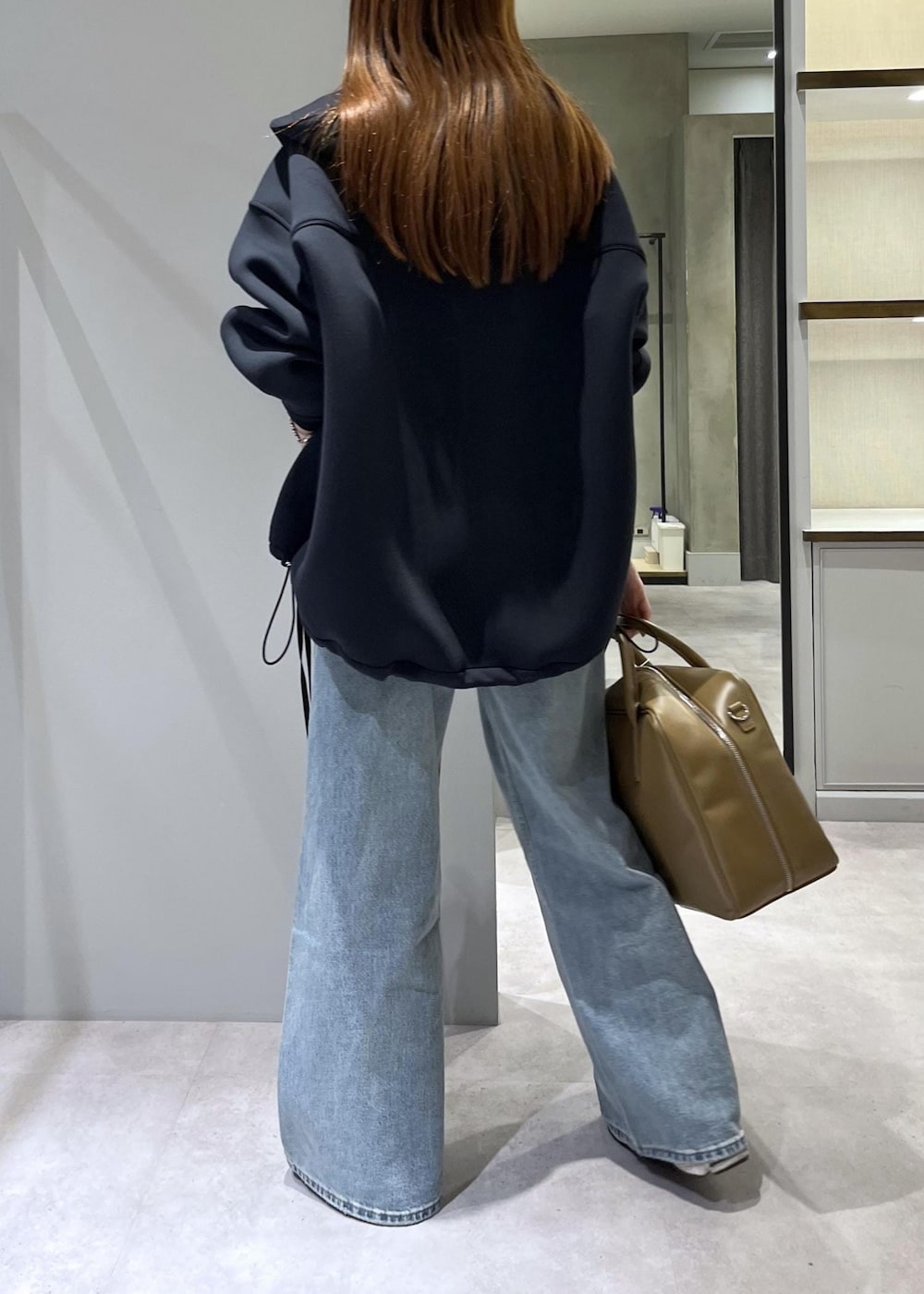 ブラウン系のボストンバッグ、ブラック系のブルゾンを着用したレディースの春コーディネートの3枚目の写真