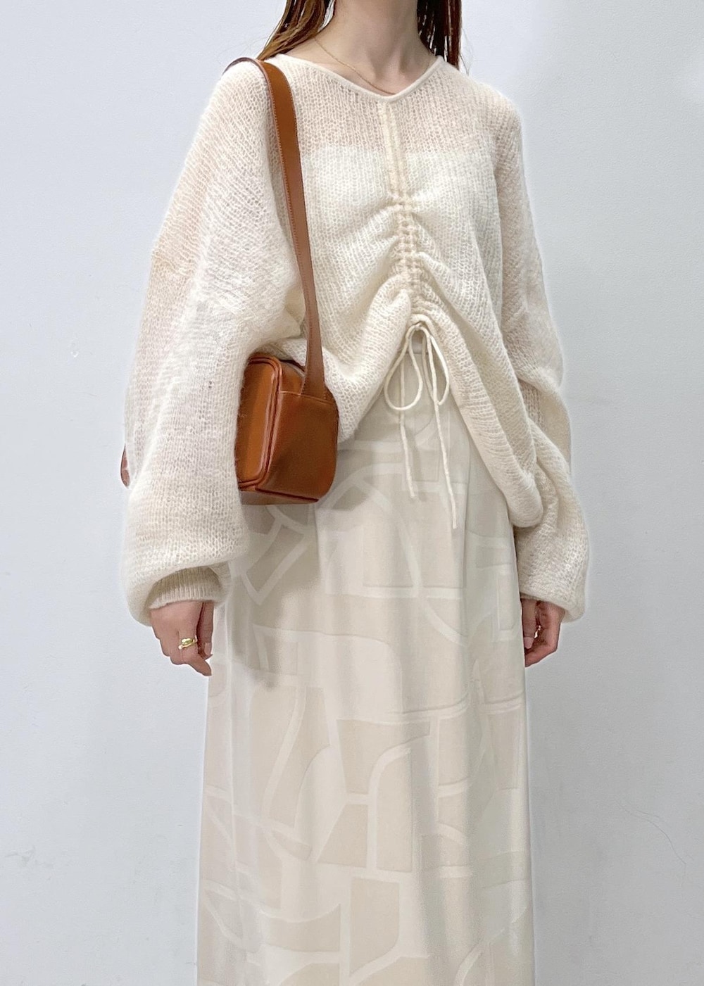 ホワイト系のスカート、ベージュ系のニット/セーター、ブラウン系のショルダーバッグを着用したレディースの夏コーディネートの6枚目の写真