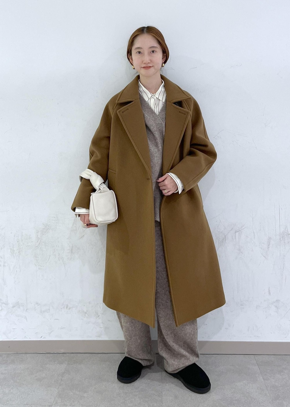ホワイト系のハンドバッグ、イエロー系のステンカラーコート、ベージュ系のニット/セーターを着用したレディースの秋コーディネートの2枚目の写真