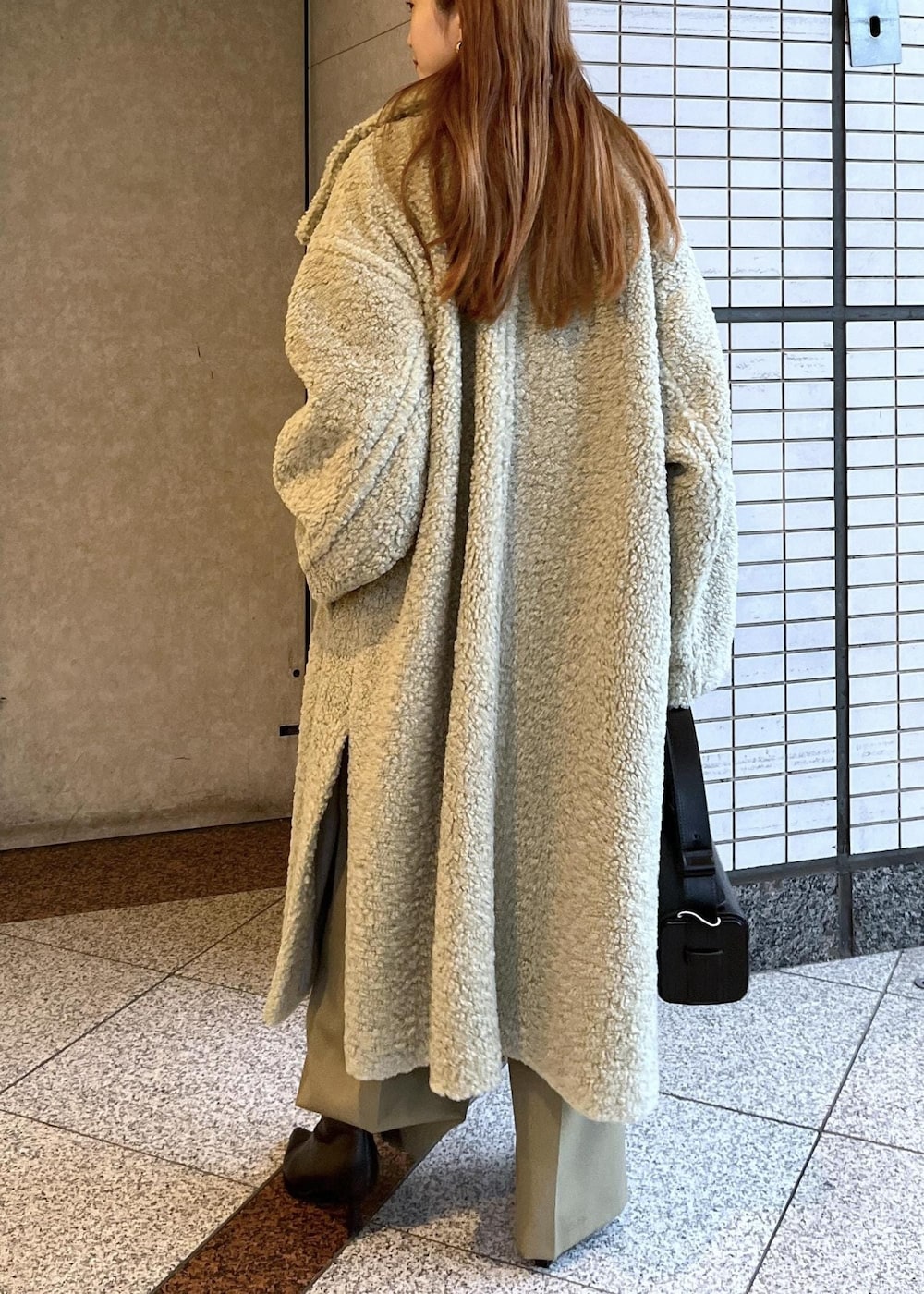 ブラック系のブーツ、ホワイト系のカーディガン/ボレロ、グリーン系のその他アウターを着用したレディースの冬コーディネートの5枚目の写真