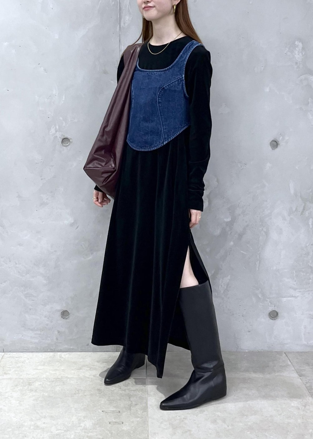 ブラック系のブーツ、ブラック系のワンピース、ブルー系のベストを着用したレディースの秋コーディネートの2枚目の写真