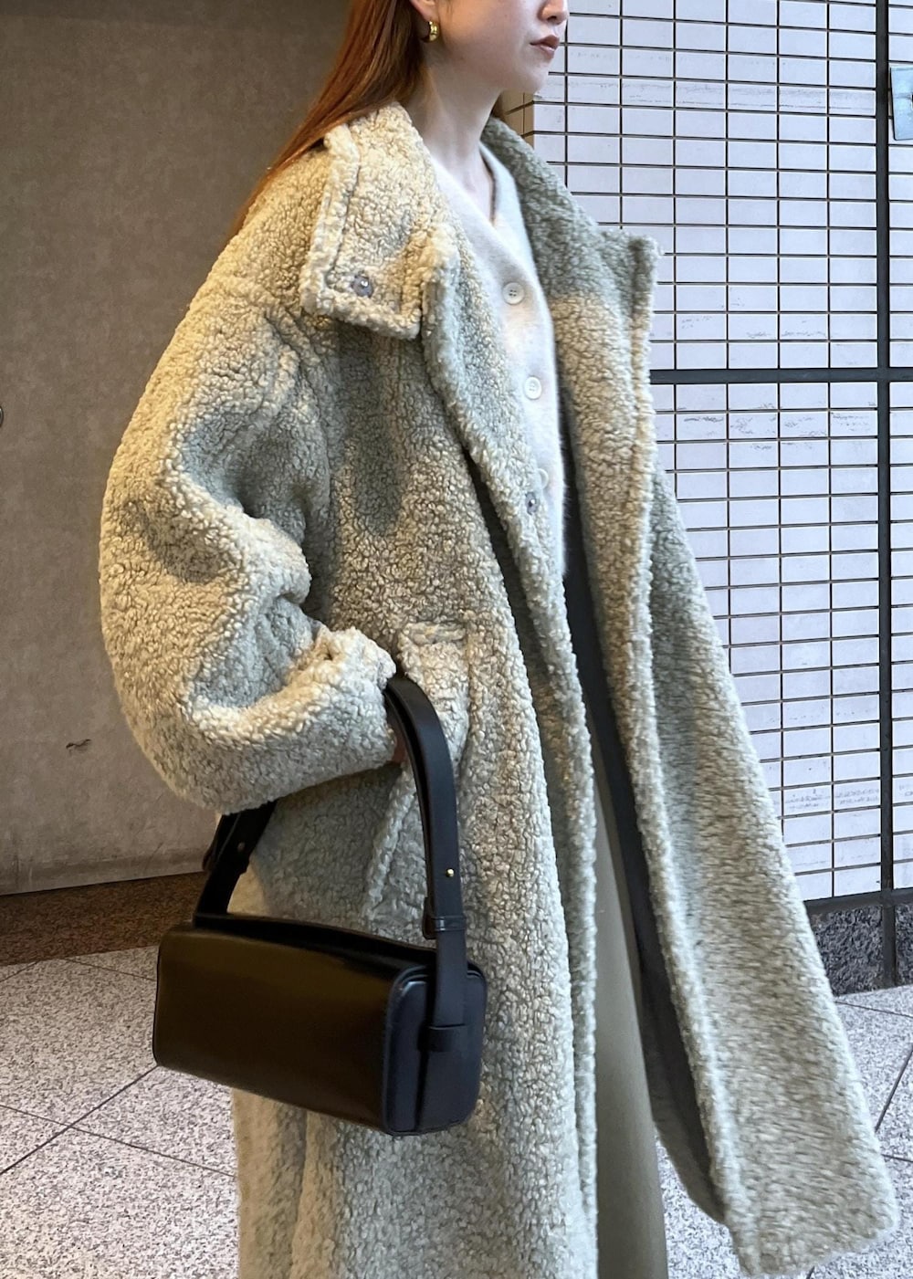 ブラック系のブーツ、ホワイト系のカーディガン/ボレロ、グリーン系のその他アウターを着用したレディースの冬コーディネートの7枚目の写真