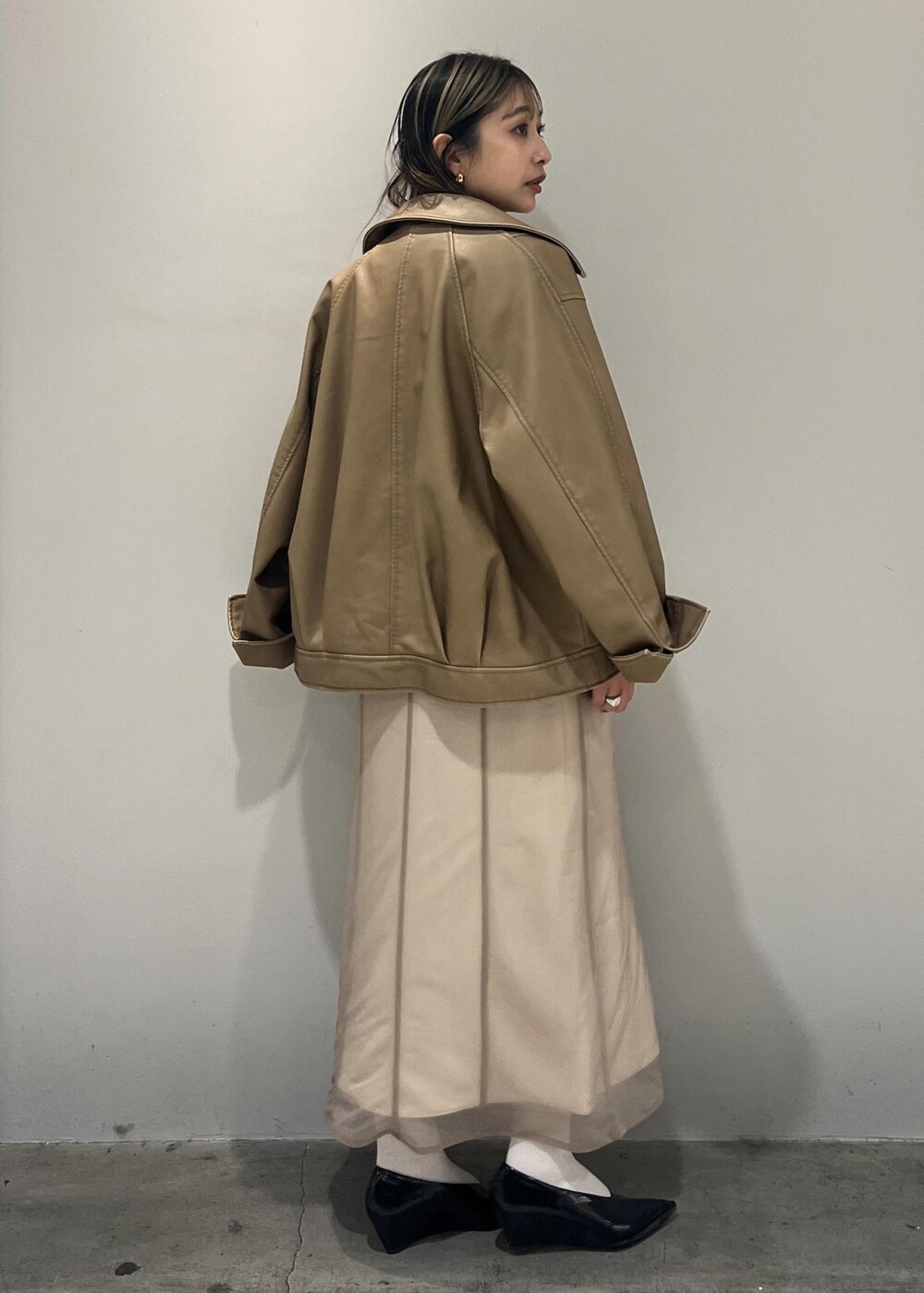 ベージュ系のワンピース、ベージュ系のライダースジャケット、ホワイト系のショルダーバッグを着用したレディースの秋コーディネートの5枚目の写真