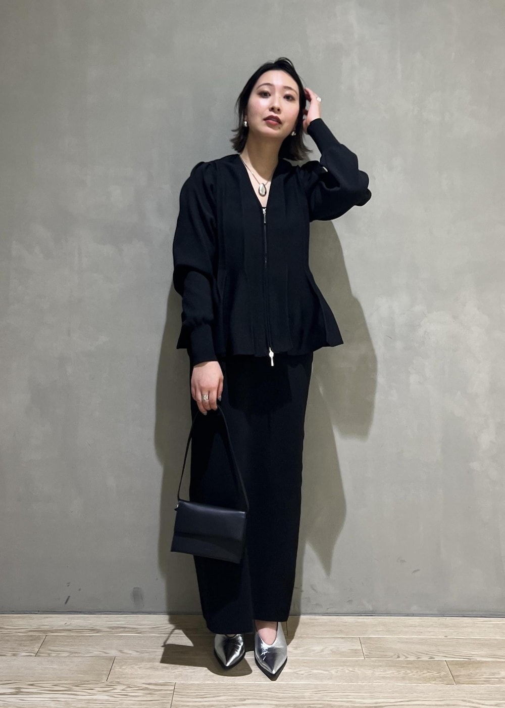 シルバー系のパンプス、ブラック系のカーディガン/ボレロ、ブラック系のワンピースを着用したレディースの春コーディネートの2枚目の写真
