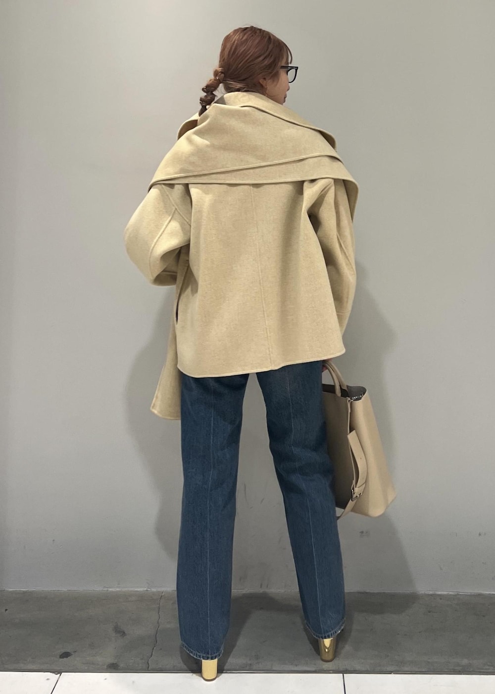 ブラック系のトートバッグ、ベージュ系のその他アウター、ブルー系のデニムパンツを着用したレディースの冬コーディネートの6枚目の写真