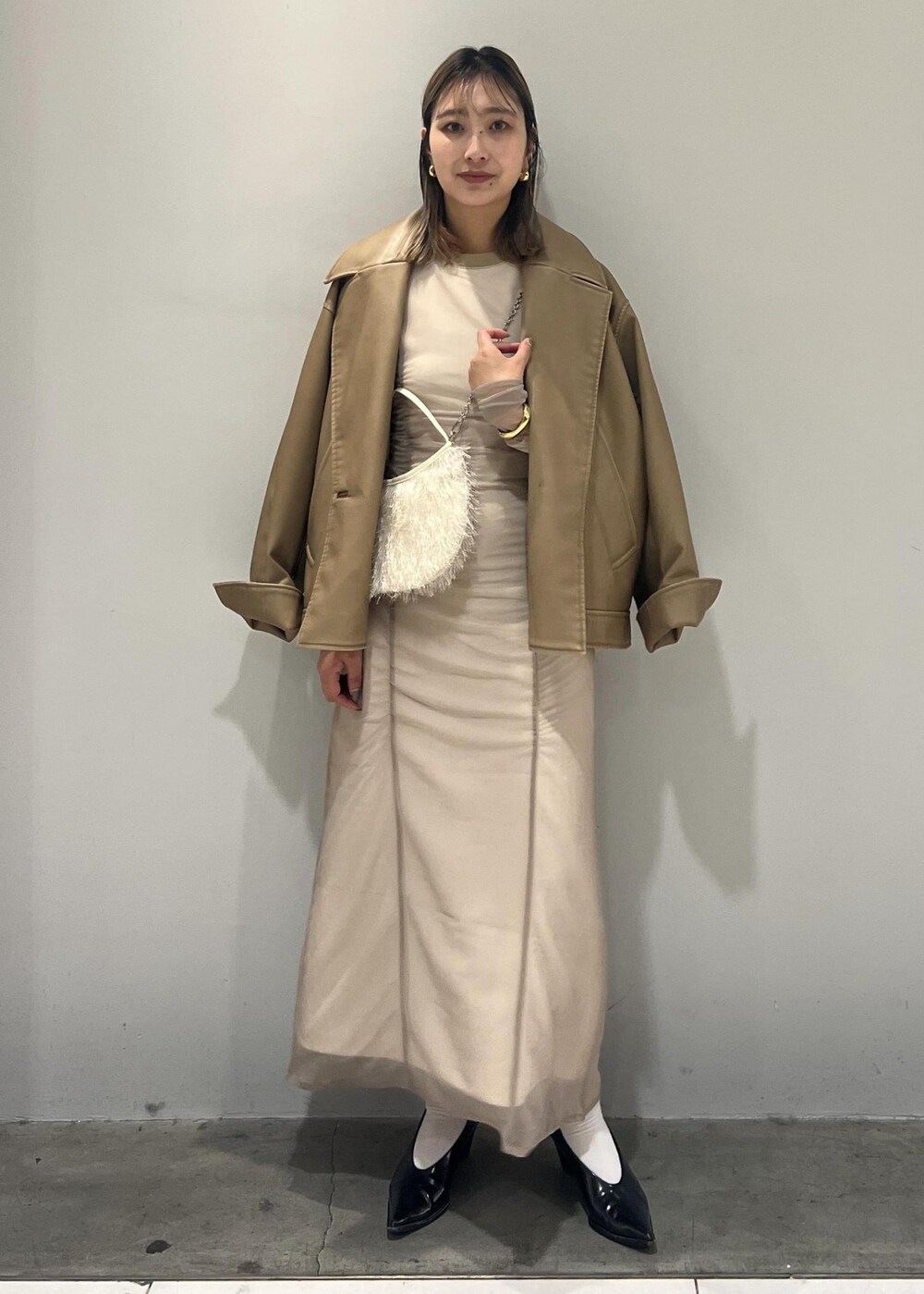 ベージュ系のワンピース、ベージュ系のライダースジャケット、ホワイト系のショルダーバッグを着用したレディースの秋コーディネートの4枚目の写真