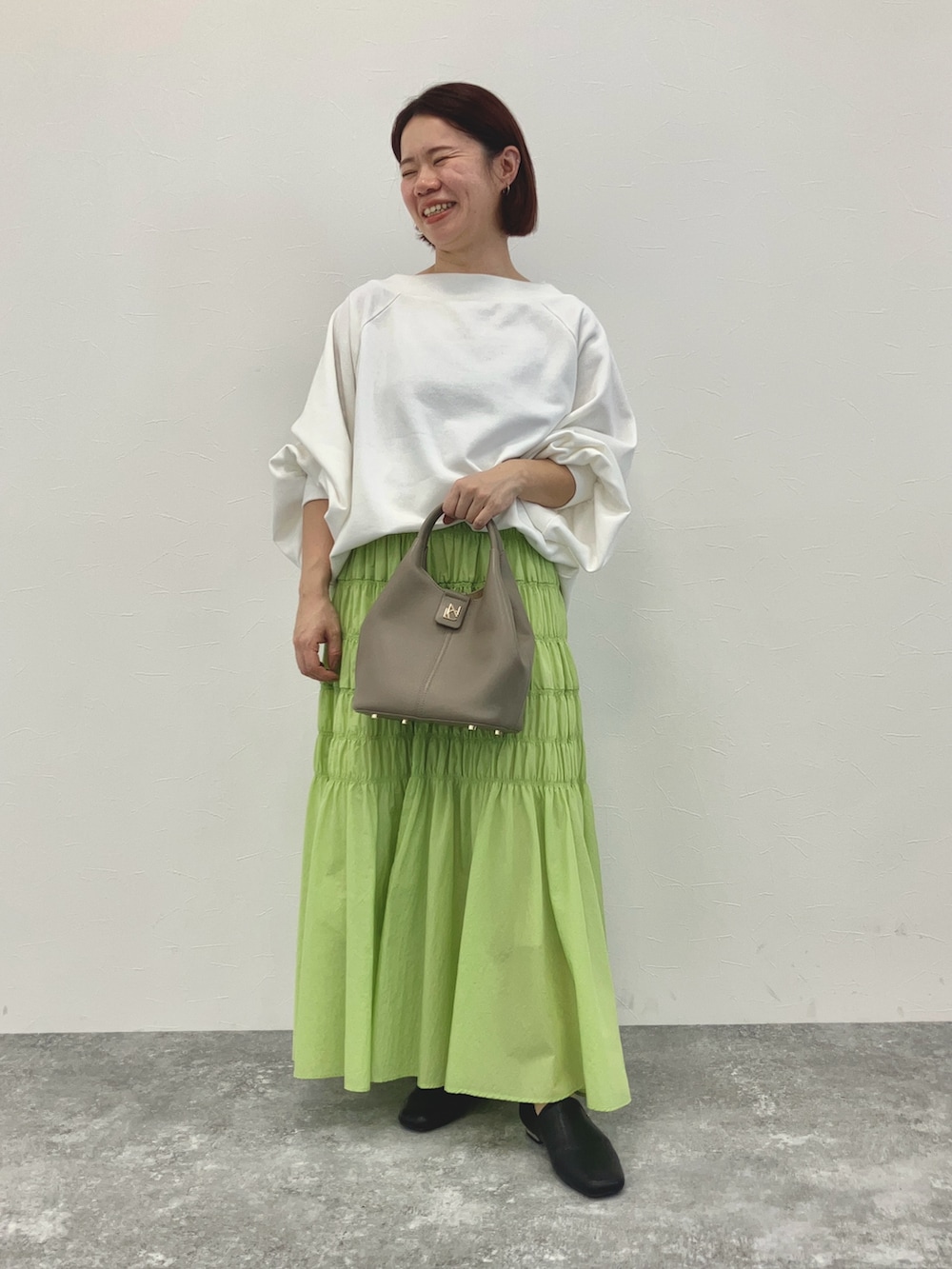 グレー系のショルダーバッグ、ホワイト系のトップス、ホワイト系のスリッポンを着用したレディースの冬コーディネートの3枚目の写真