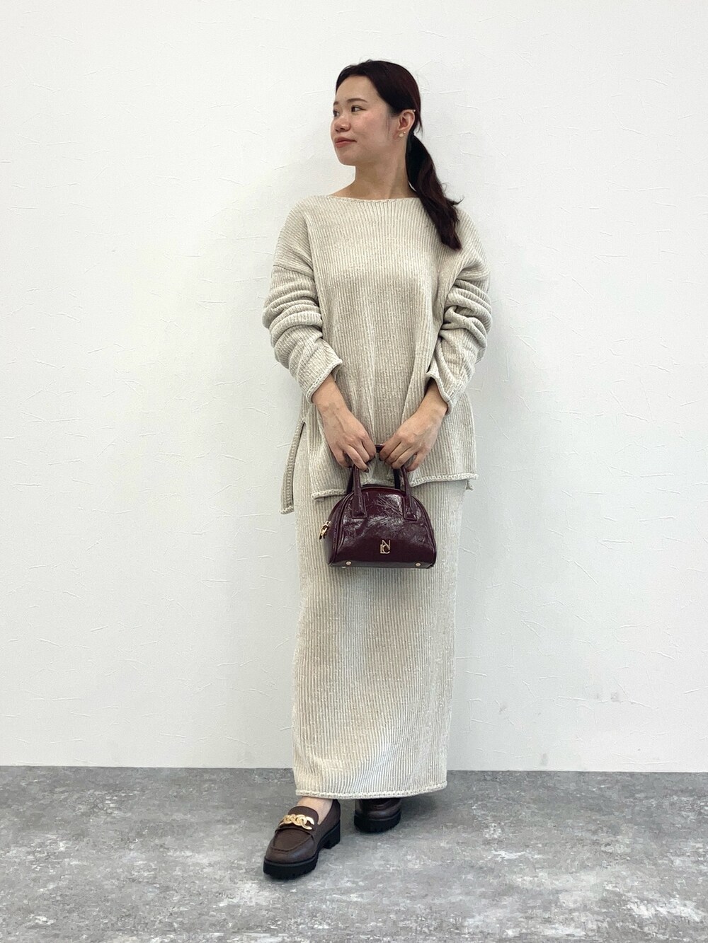 ホワイト系のスカート、レッド系のショルダーバッグ、ブラウン系のローファーを着用したレディースの秋コーディネートの2枚目の写真