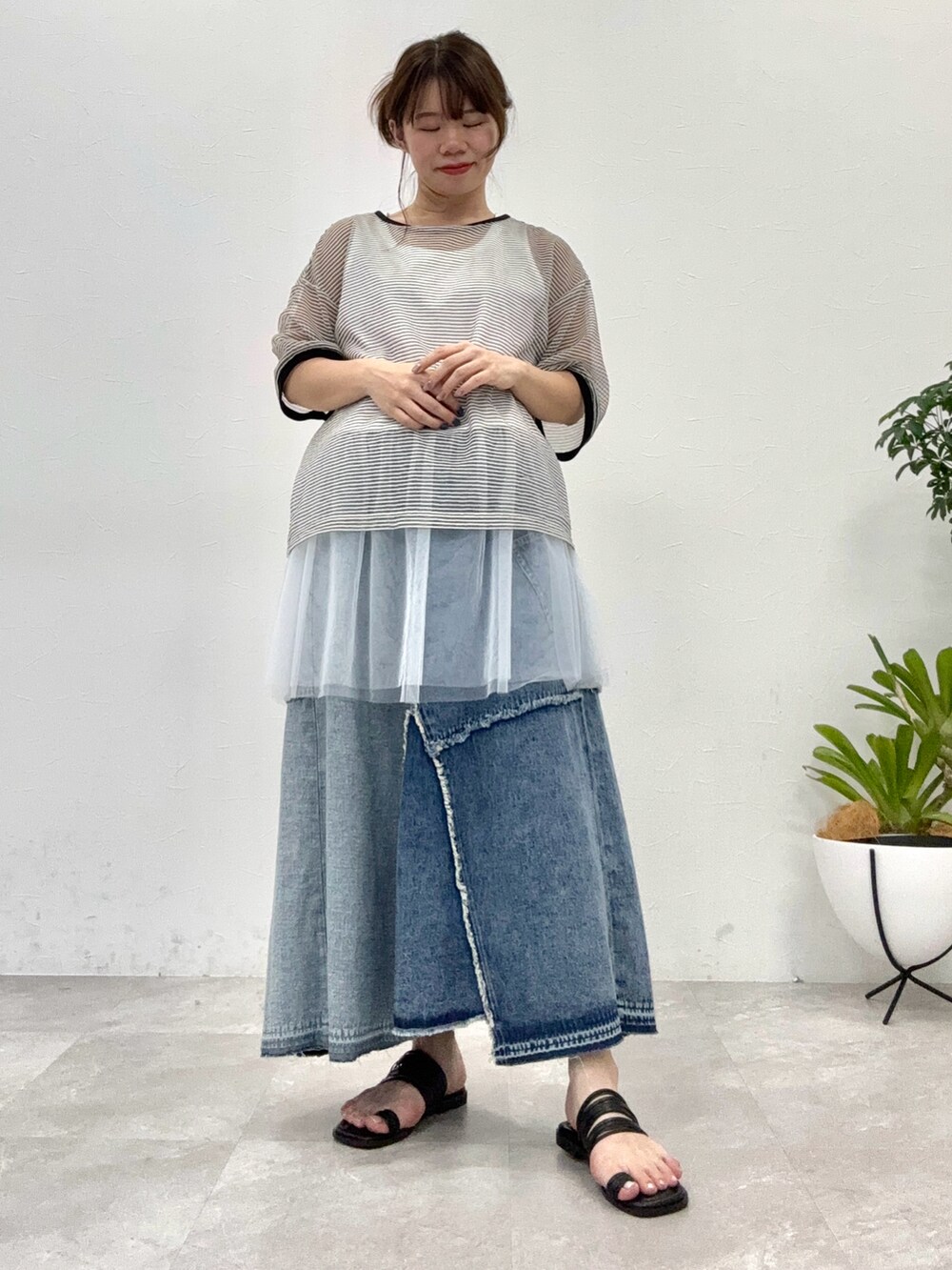 ブラック系のサンダル、ブルー系のデニムスカート、ブラック系のTシャツ/カットソーを着用したレディースの春コーディネートの2枚目の写真