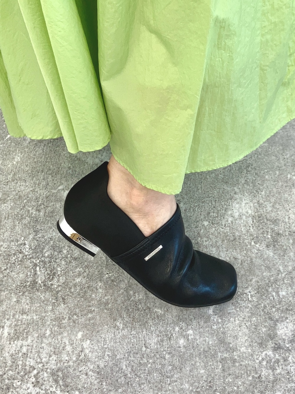 グレー系のショルダーバッグ、ホワイト系のトップス、ホワイト系のスリッポンを着用したレディースの冬コーディネートの2枚目の写真