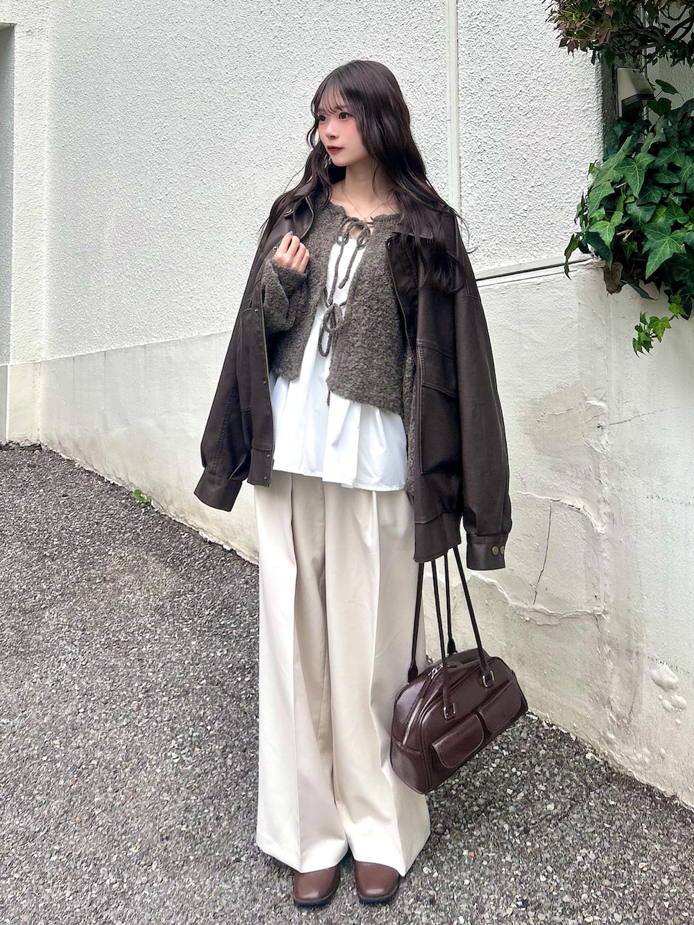 ブラウン系のカーディガン/ボレロ、ブラウン系のブルゾン、ブラウン系のボストンバッグを着用したレディースの秋コーディネートの2枚目の写真