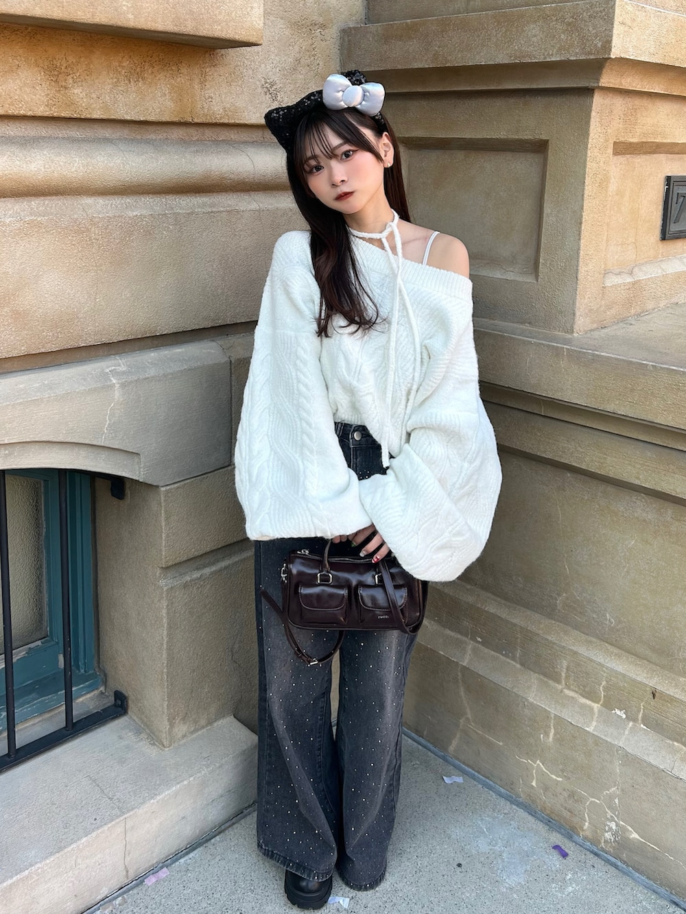 ブラック系のその他アウター、ホワイト系のニット/セーター、ブラウン系のボストンバッグを着用したレディースの冬コーディネートの2枚目の写真