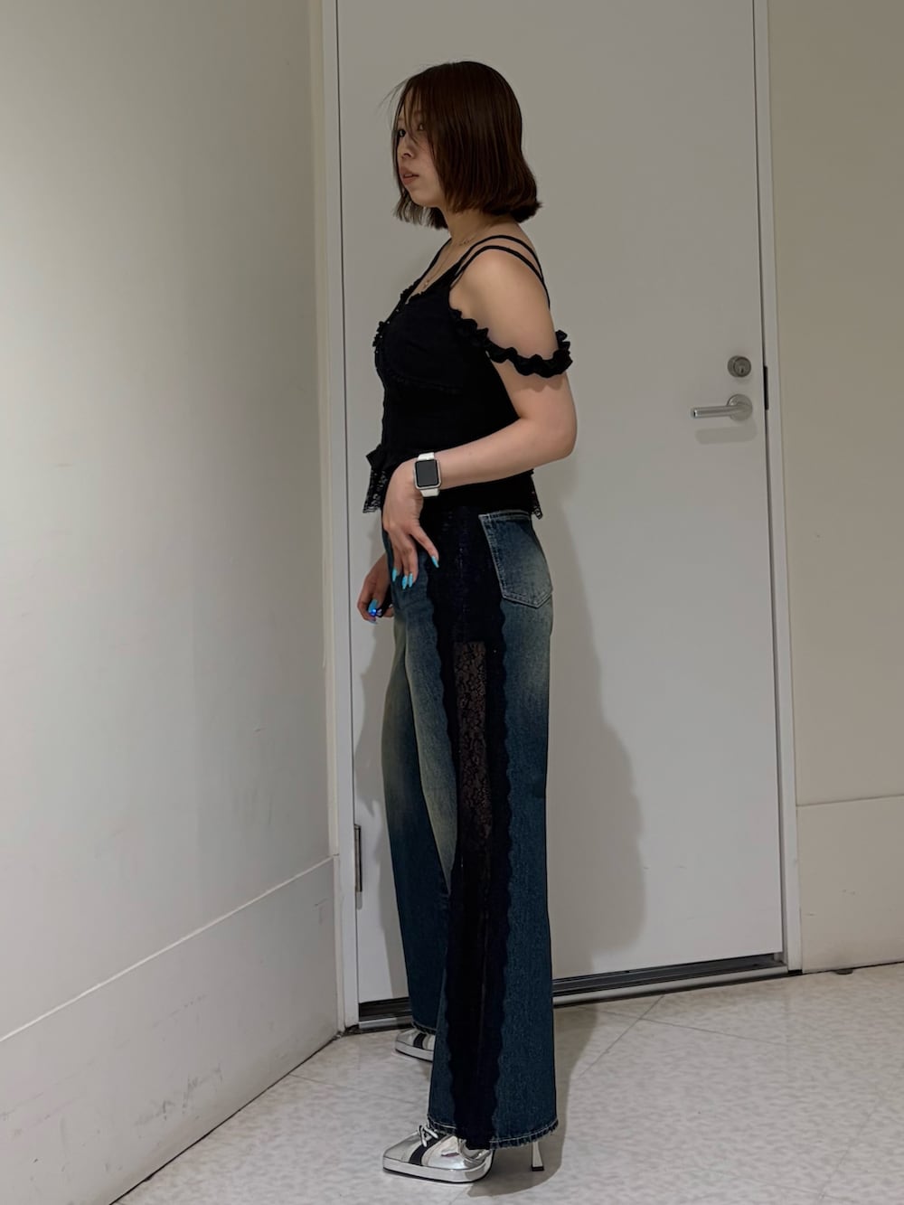 ブラック系のキャミソール、ブルー系のデニムパンツ、ブラック系のサンダルを着用したレディースの春コーディネートの2枚目の写真