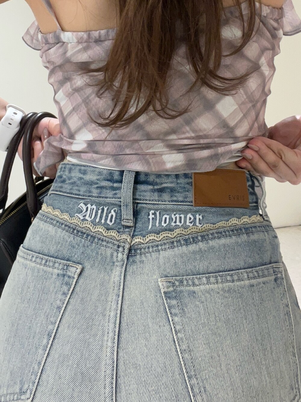 ピンク系のキャミソール、ブルー系のデニムパンツ、ブラック系のショルダーバッグを着用したレディースの春コーディネートの4枚目の写真