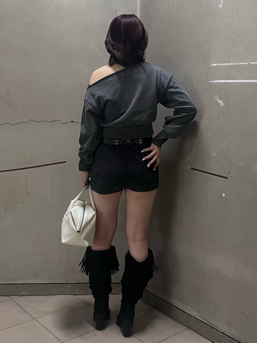 ブラック系のブーツ、ホワイト系のボストンバッグ、ブラック系のその他パンツを着用したレディースの冬コーディネートの3枚目の写真