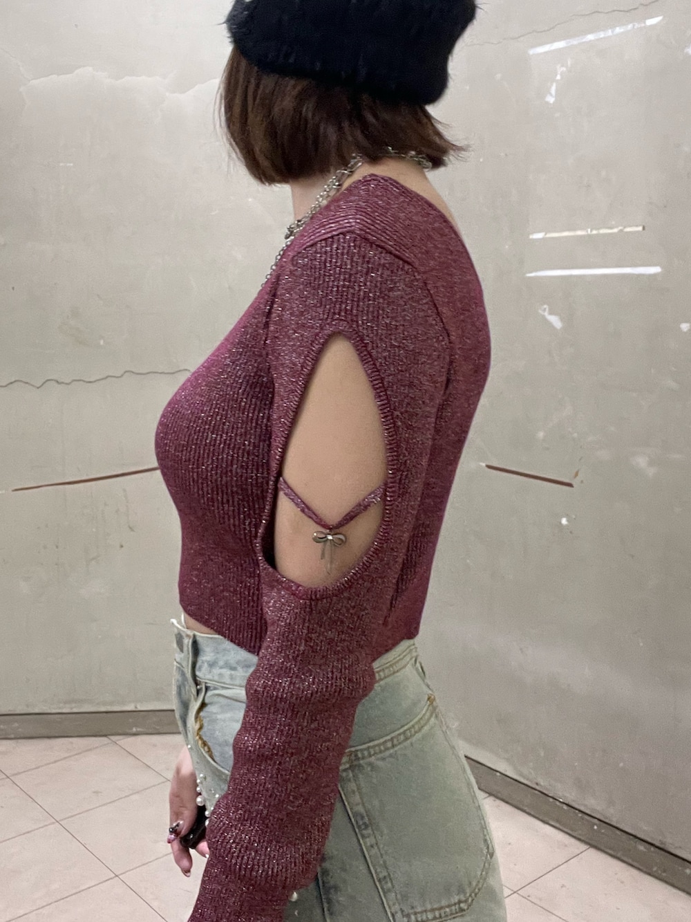 ホワイト系のチェスターコート、レッド系のニット/セーター、ブルー系のデニムパンツを着用したレディースの冬コーディネートの5枚目の写真