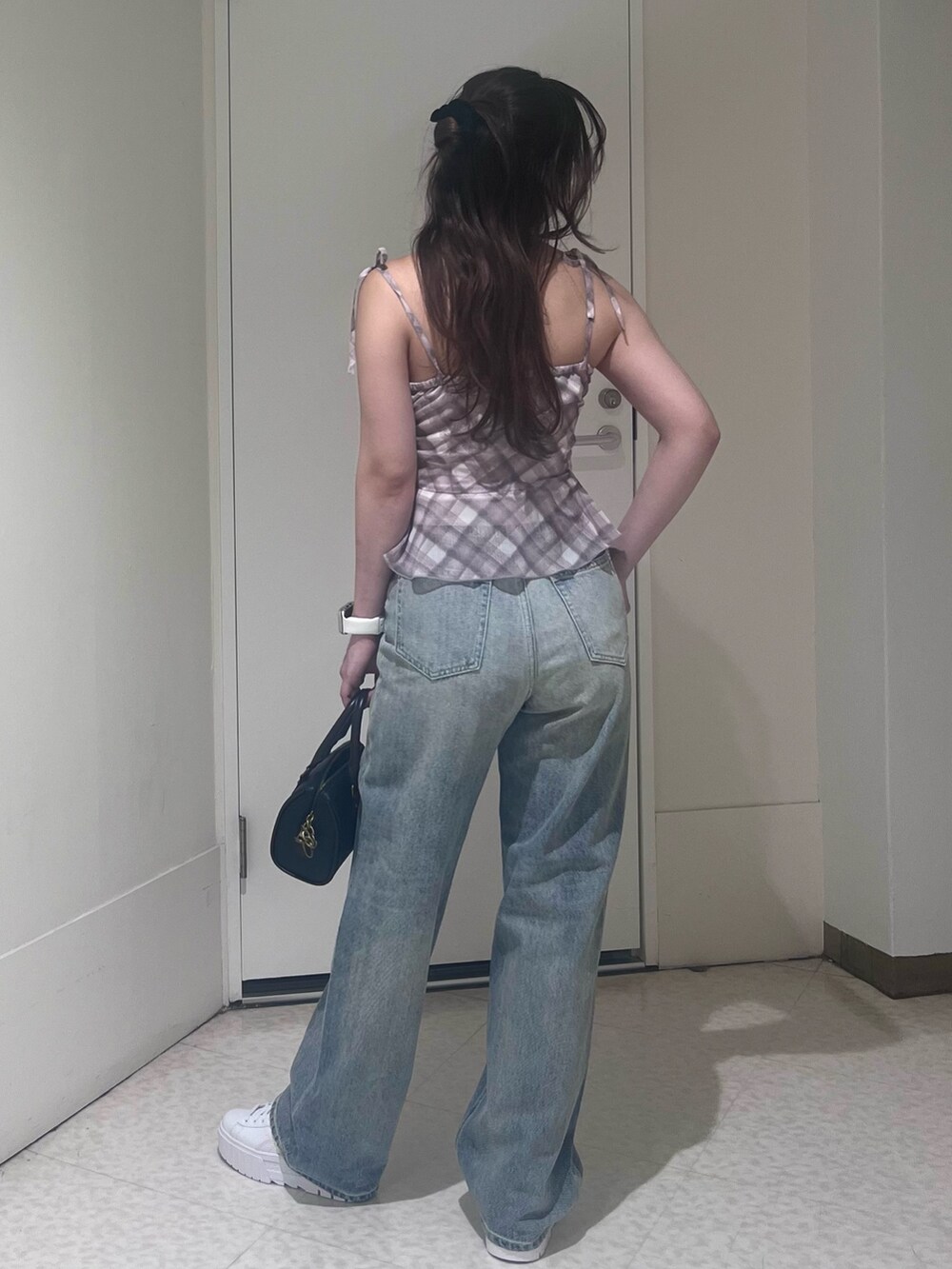 ピンク系のキャミソール、ブルー系のデニムパンツ、ブラック系のショルダーバッグを着用したレディースの春コーディネートの3枚目の写真