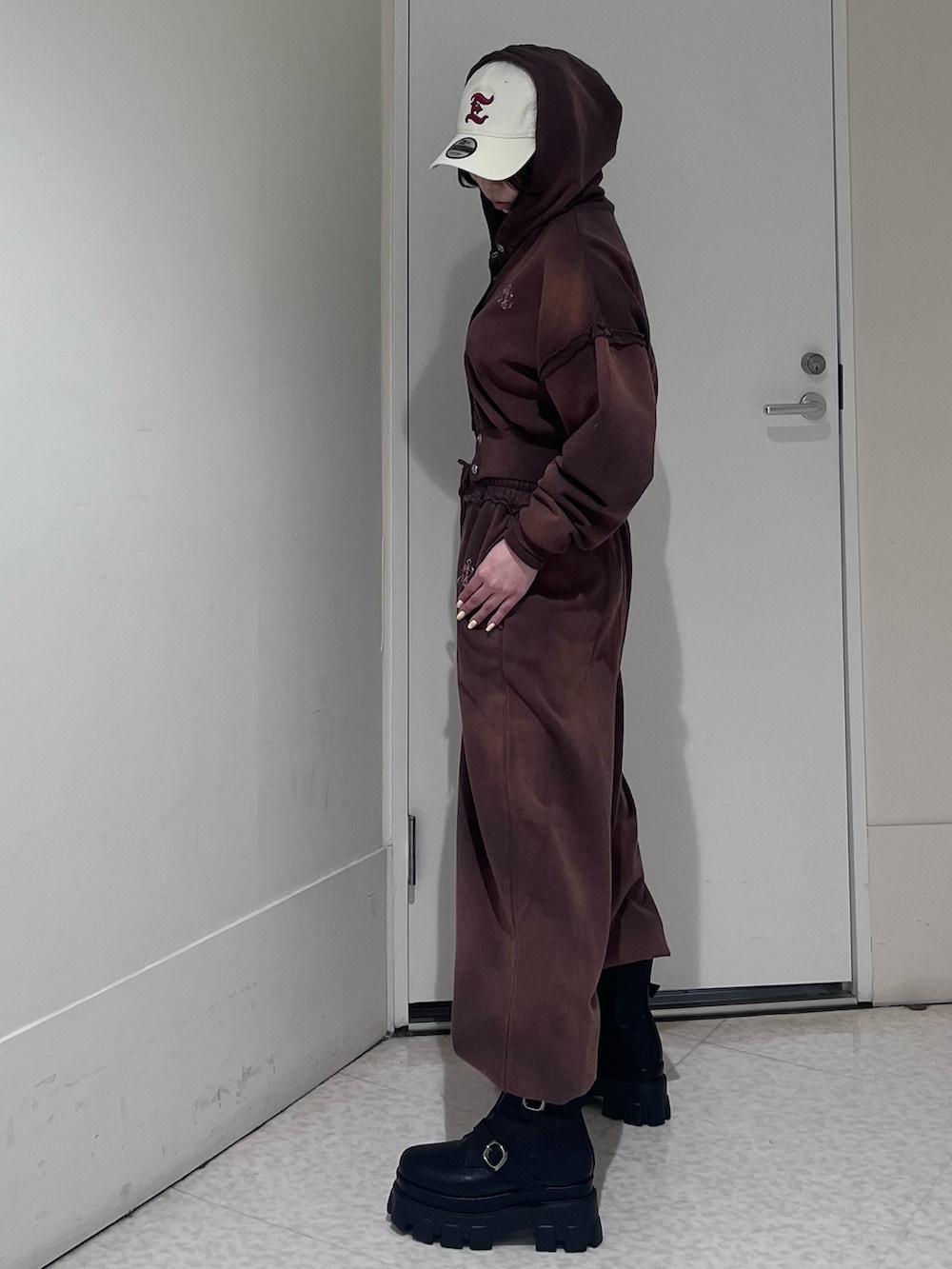 ブラウン系のパーカー、ブラウン系のスウェットパンツ、ブラック系のブーツを着用したレディースの春コーディネートの2枚目の写真