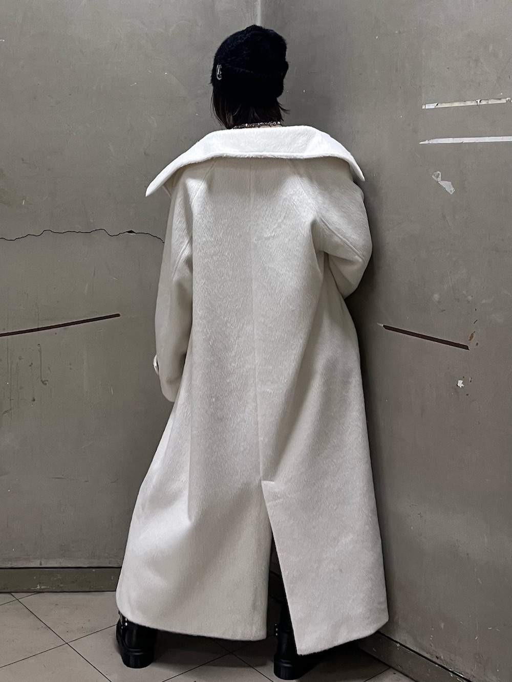 ホワイト系のチェスターコート、レッド系のニット/セーター、ブルー系のデニムパンツを着用したレディースの冬コーディネートの3枚目の写真