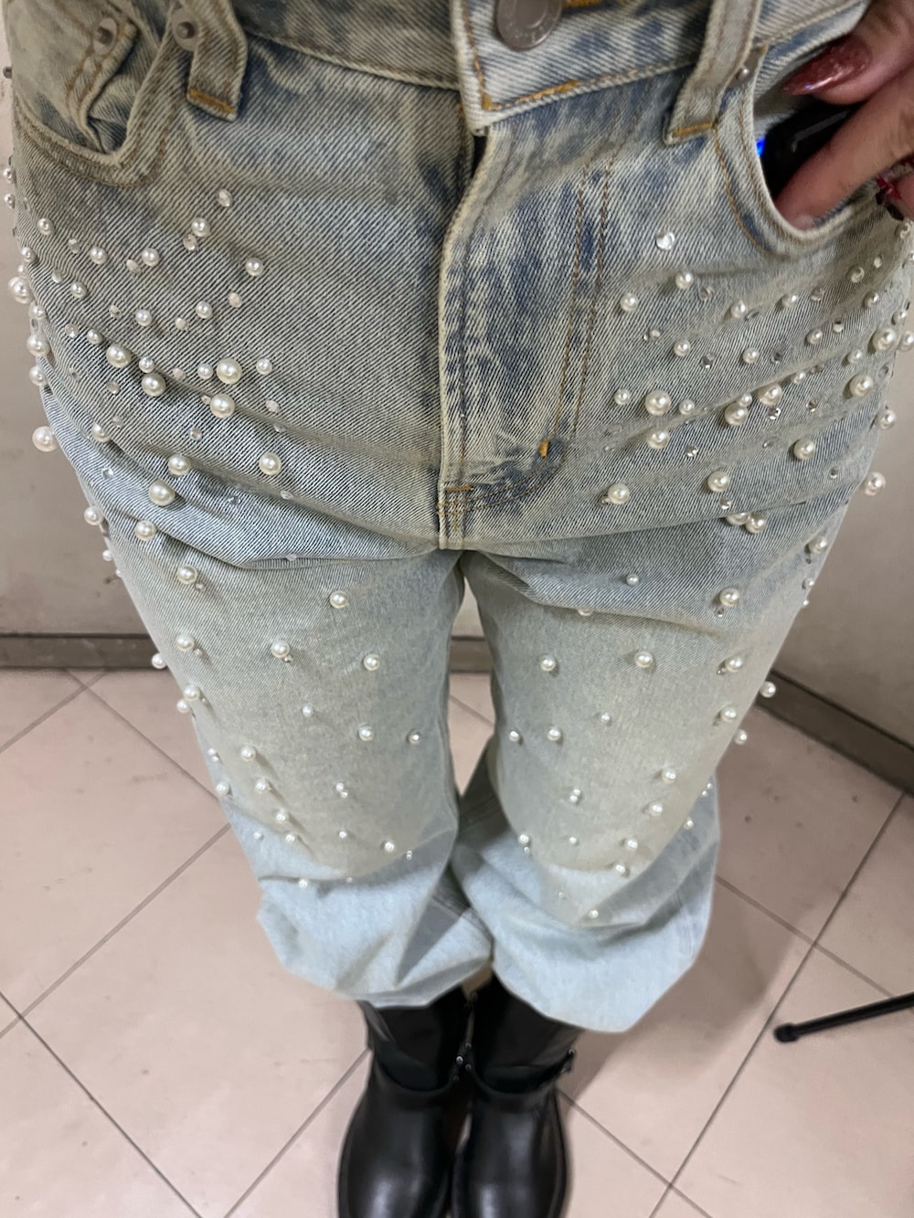 ホワイト系のチェスターコート、レッド系のニット/セーター、ブルー系のデニムパンツを着用したレディースの冬コーディネートの6枚目の写真