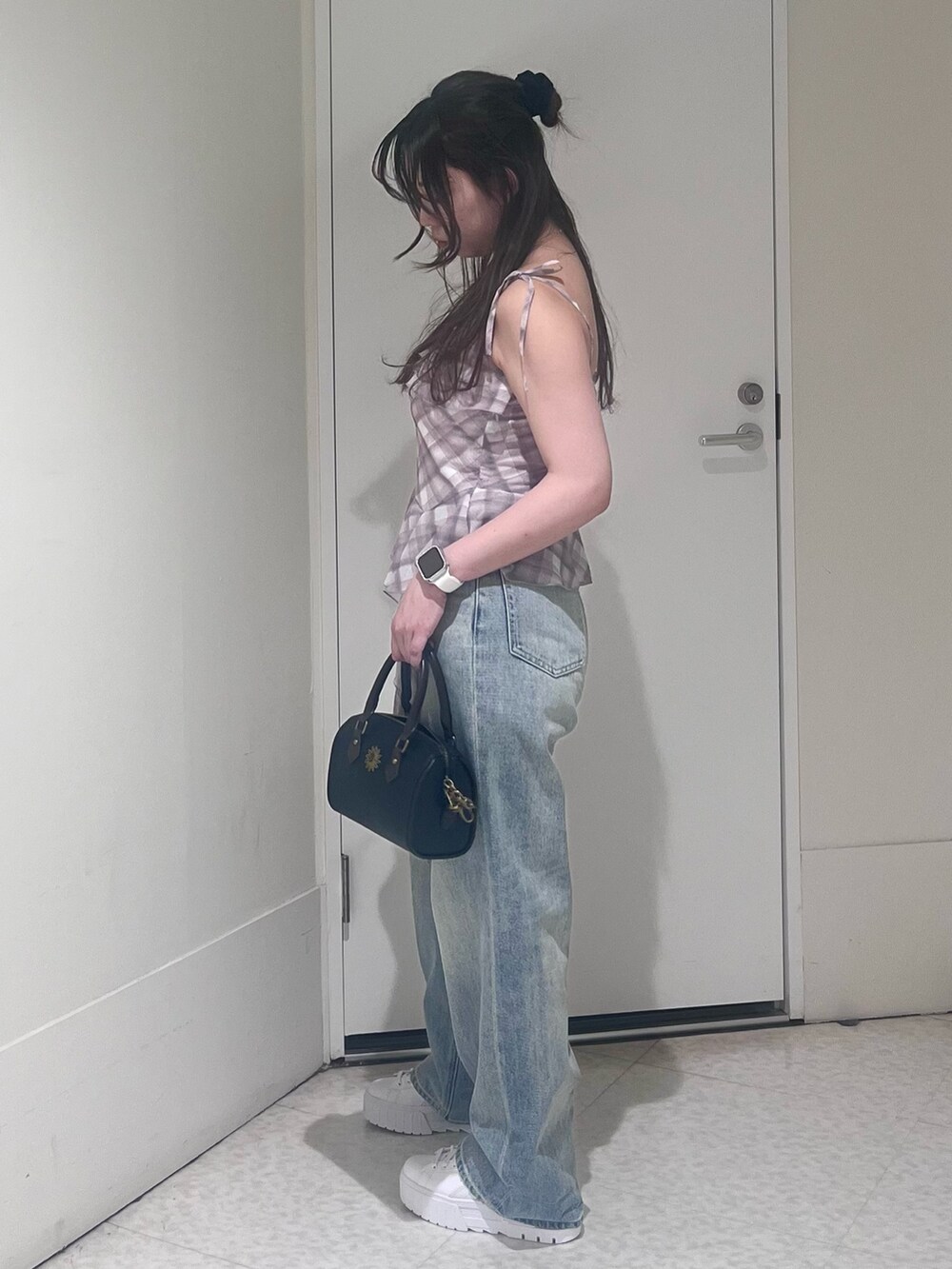 ピンク系のキャミソール、ブルー系のデニムパンツ、ブラック系のショルダーバッグを着用したレディースの春コーディネートの2枚目の写真