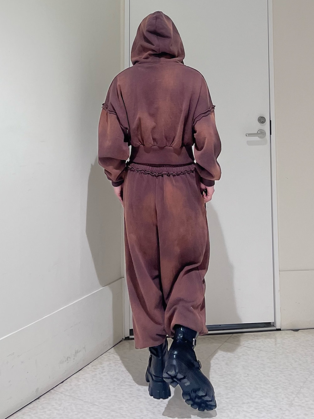 ブラウン系のパーカー、ブラウン系のスウェットパンツ、ブラック系のブーツを着用したレディースの春コーディネートの3枚目の写真