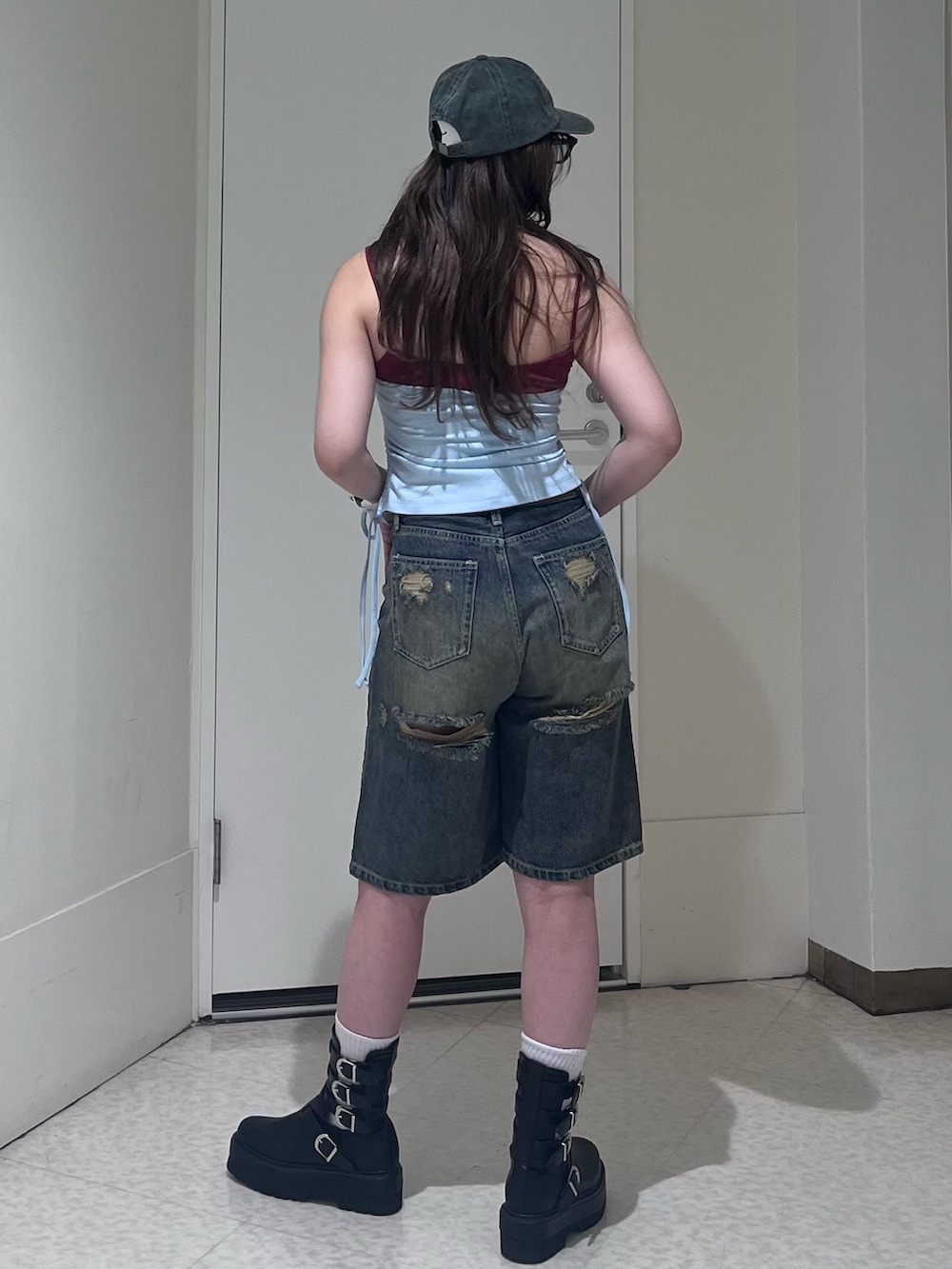 ブルー系のタンクトップ、ブルー系のデニムパンツ、ブラック系のブーツを着用したレディースの春コーディネートの3枚目の写真