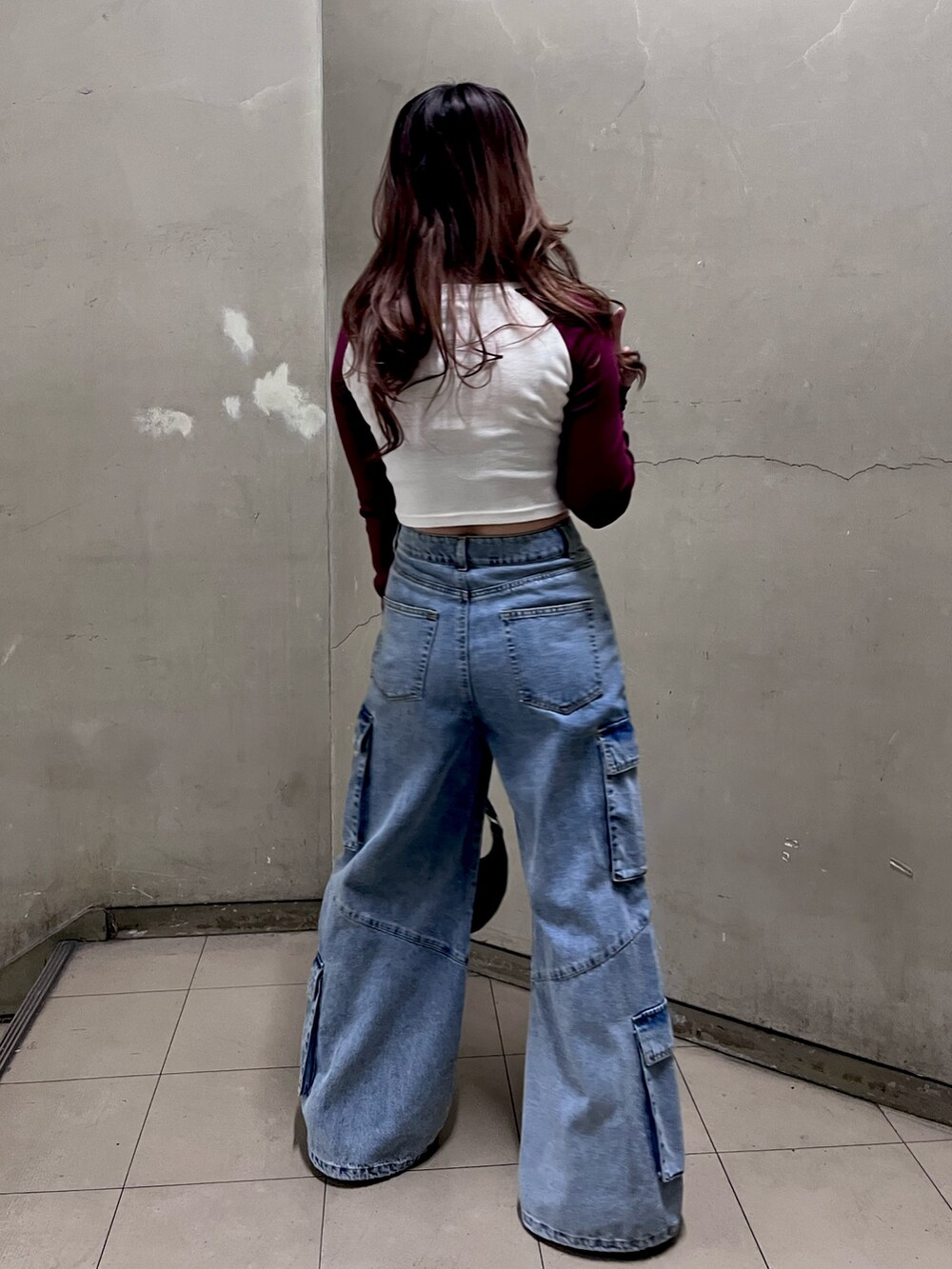 レッド系のTシャツ/カットソー、ブルー系のデニムパンツ、ブラック系のショルダーバッグを着用したレディースの春コーディネートの3枚目の写真