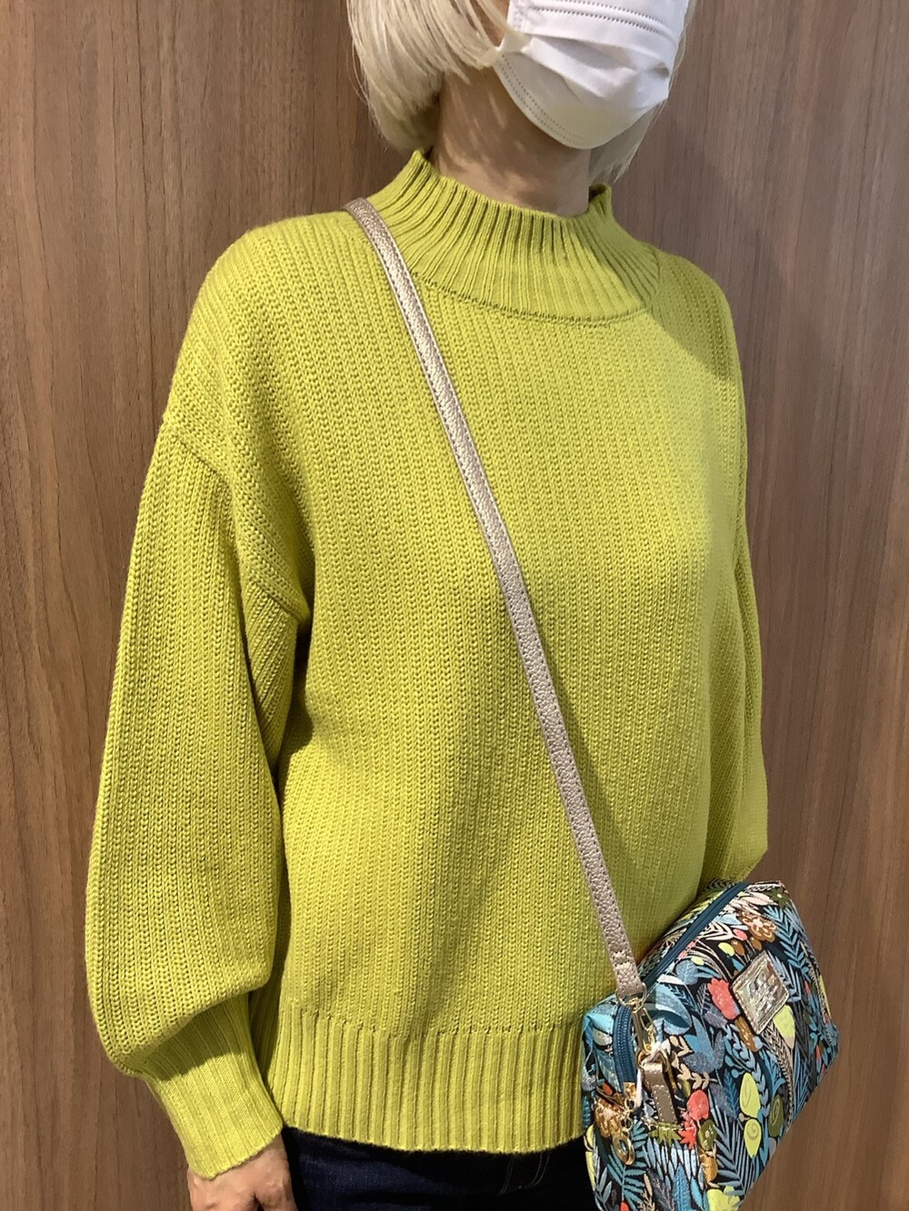 イエロー系のニット/セーター、ブラック系のその他シューズ、ゴールド系のポーチを着用したレディースの冬コーディネートの2枚目の写真