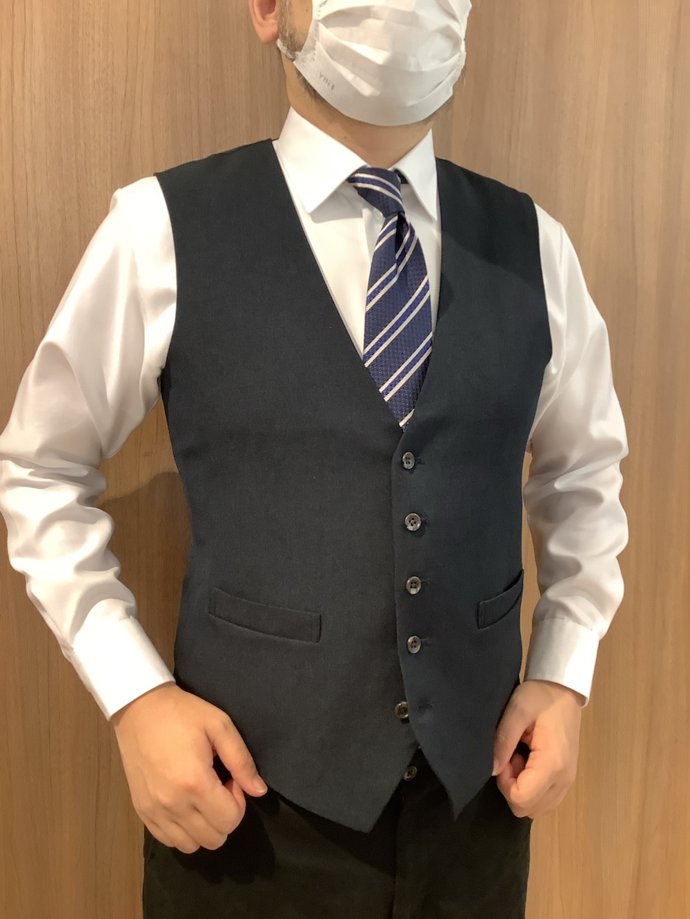 ホワイト系のビジネスシャツ、ブルー系のベスト、ブルー系のネクタイを着用したメンズの秋コーディネートの2枚目の写真