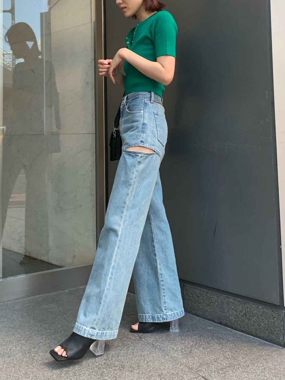 ブルー系のデニムパンツ、ブラック系のサンダル、ブラック系のショルダーバッグを着用したレディースの夏コーディネートの2枚目の写真